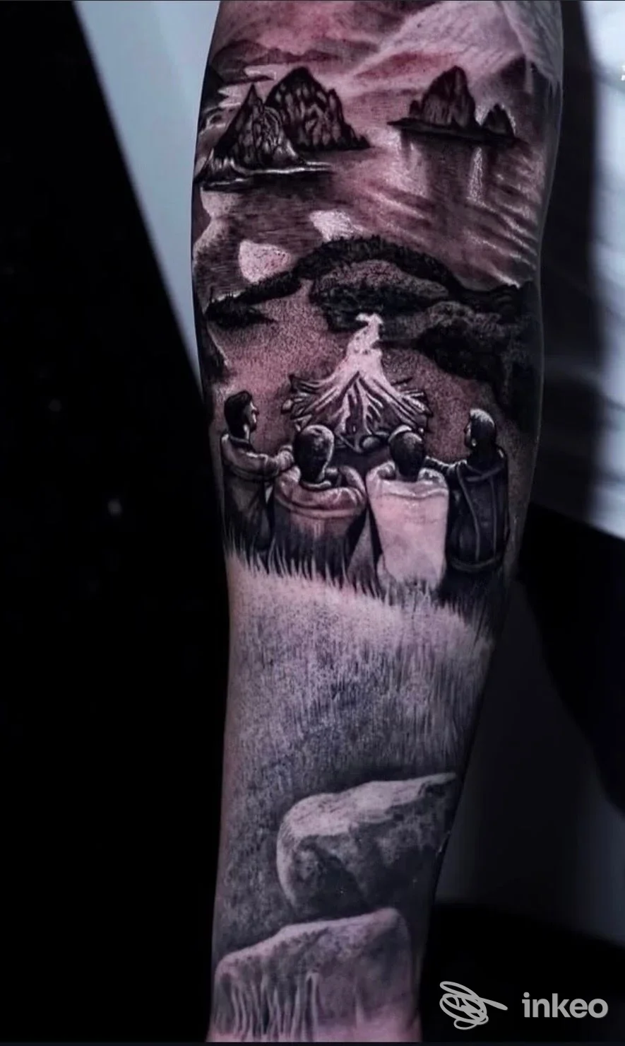 Tatuaggio realistico in bianco e nero su avambraccio raffigurante persone attorno a un falò e un paesaggio marino, Anima Tattoo Pmu, Roma.