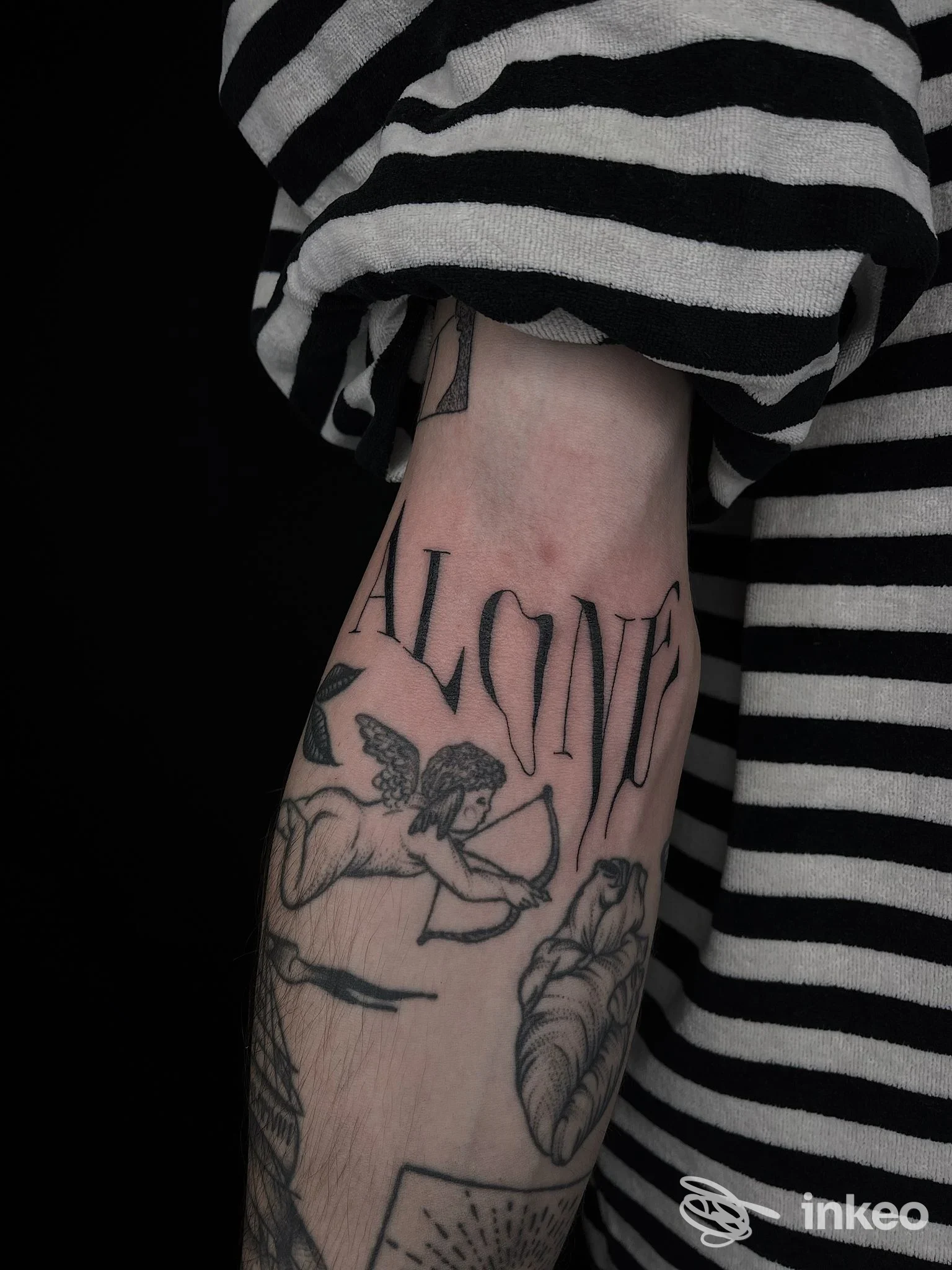 Foto dell'avambraccio con tatuaggi neri (scritta, cherubino e cuore anatomico) scattata per Anima Tattoo Studio, Sant'Angelo In Villa-giglio.