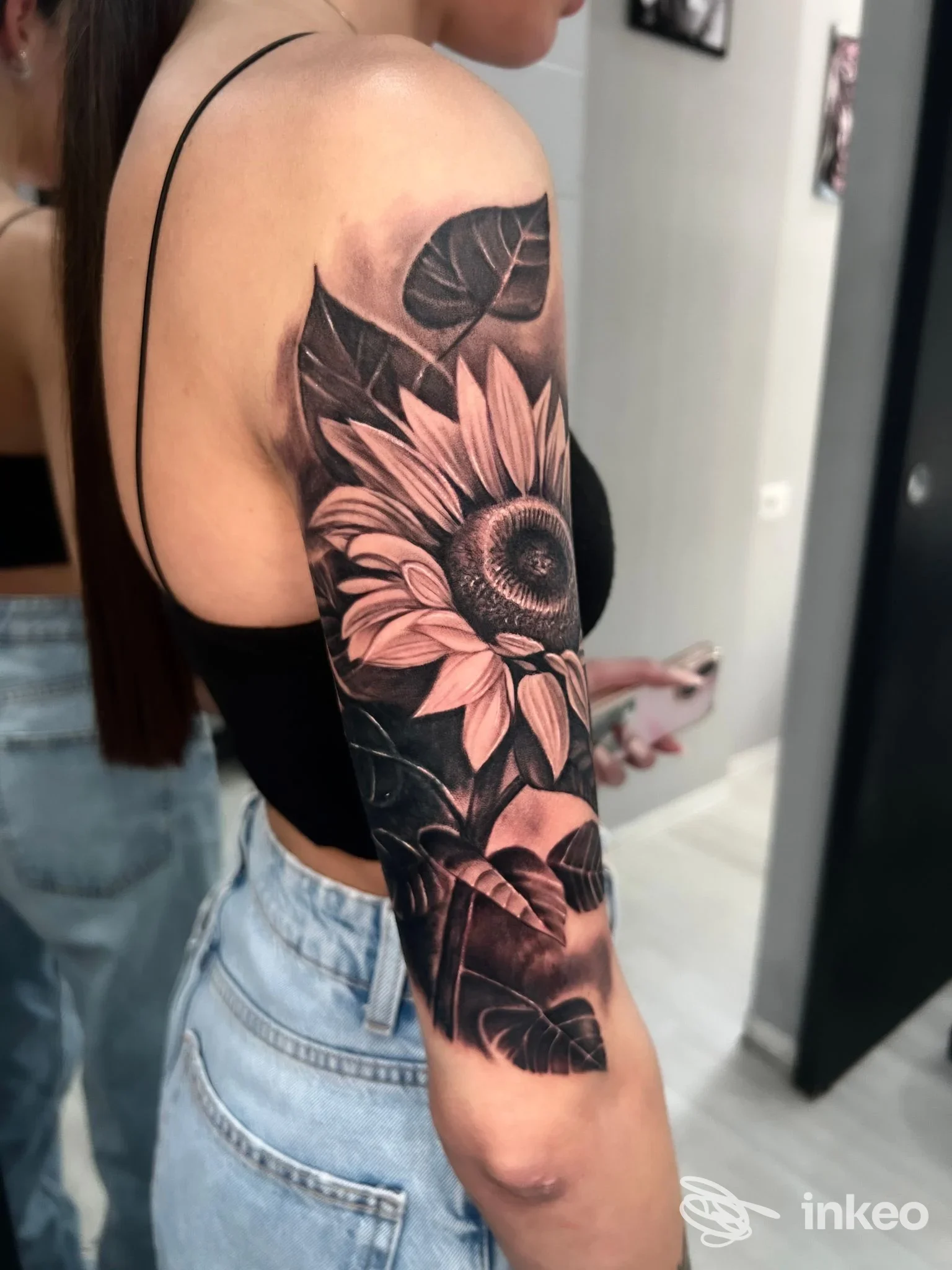 Fotografia di un tatuaggio a mezza manica con girasole realistico su spalla e braccio, realizzato da Aven Art Tattoo, Roma.