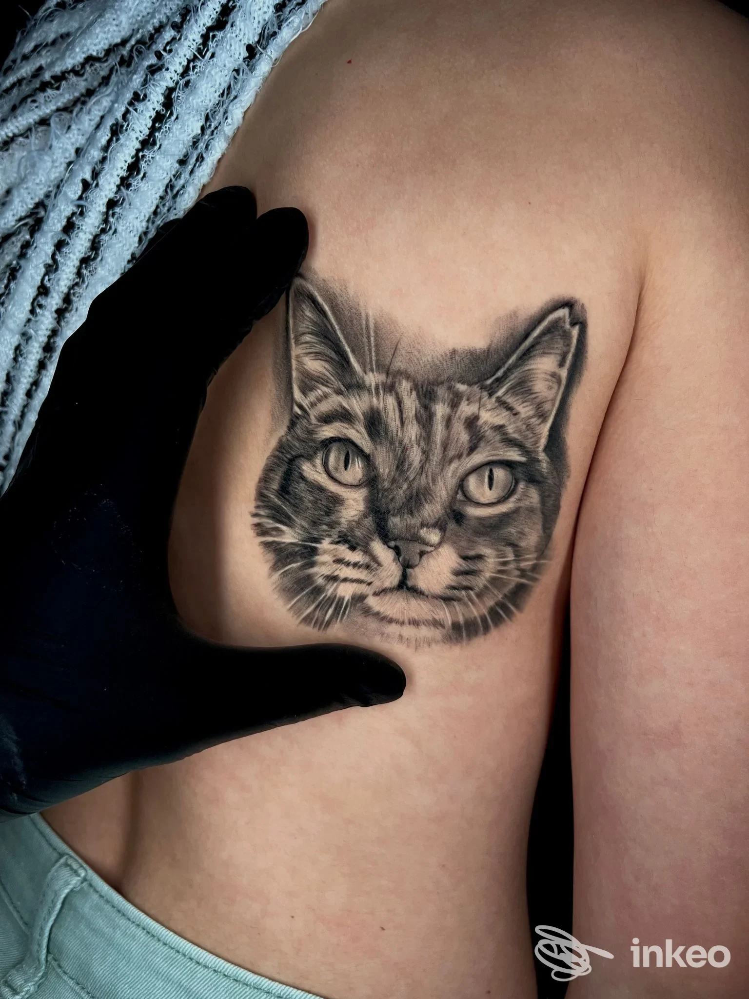 Tatuaggio realistico in nero di un muso di gatto sul fianco, foto dallo studio Aven Art Tattoo, Roma.