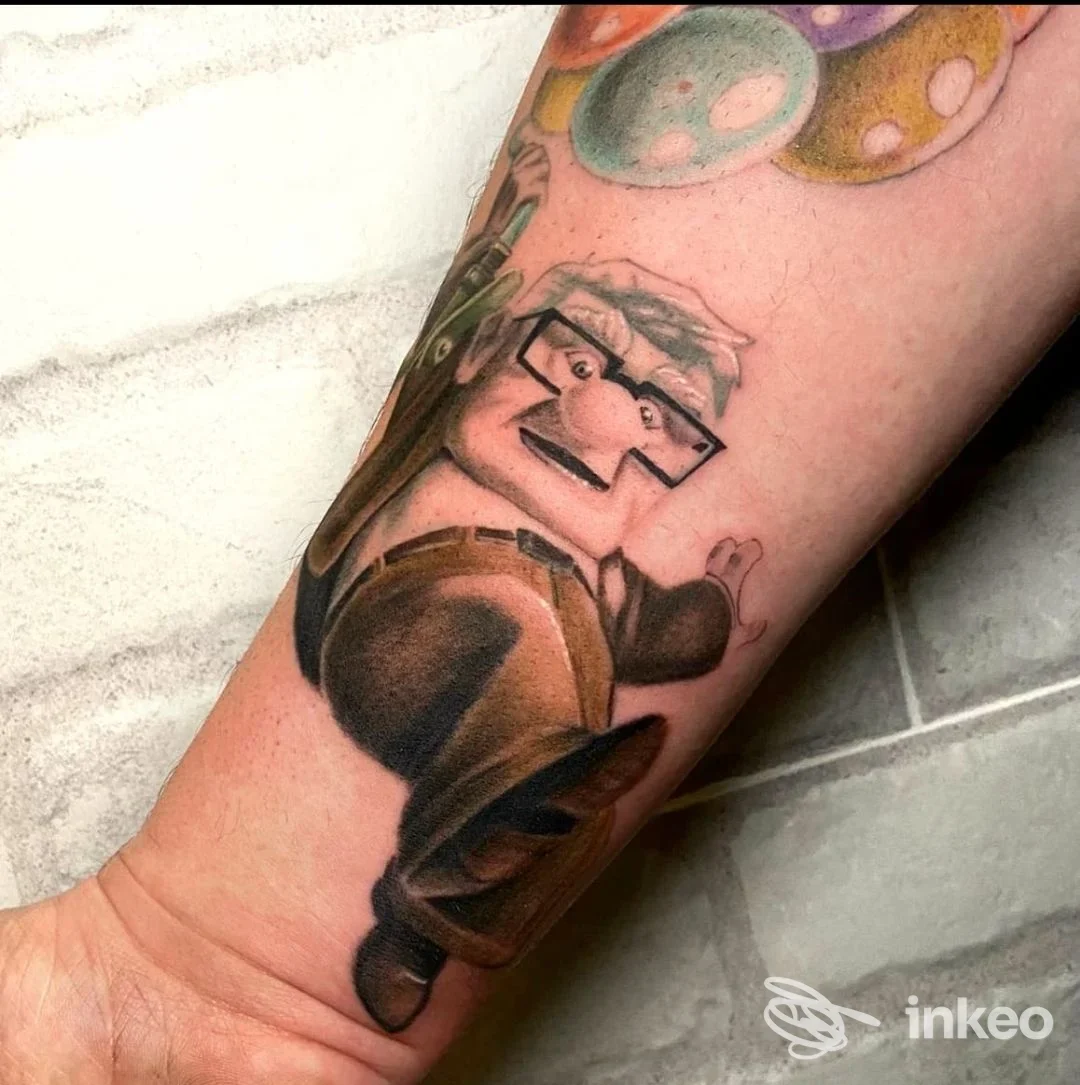 Tatuaggio sull'avambraccio raffigurante una figura cartonesca colorata, con contorni ben definiti e colori vivaci su pelle reale.