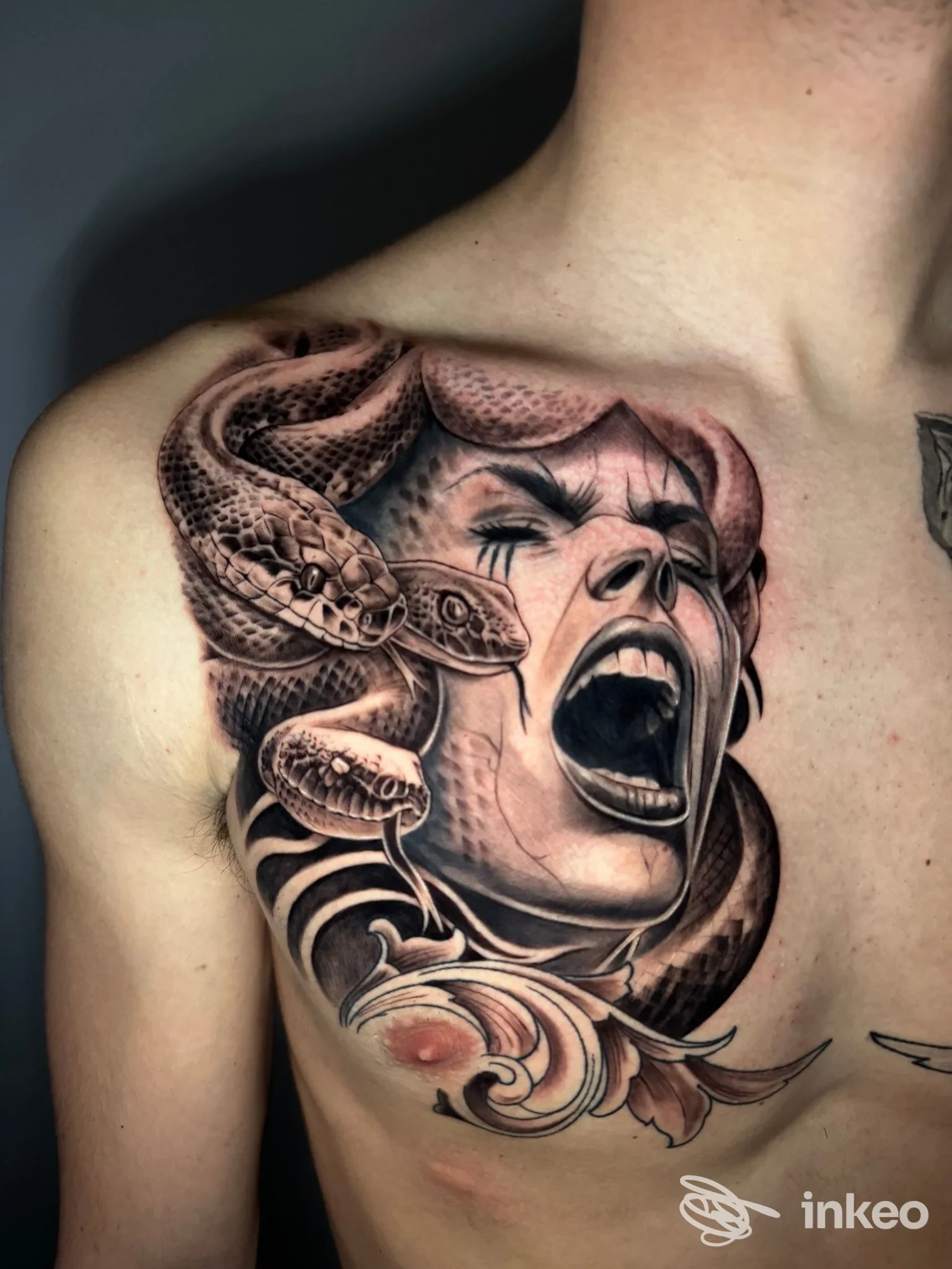 Grande tatuaggio realistico a petto e spalla sinistra con volto urlante avvolto da serpenti, Black Blood tattoo, Anguillara Sabazia.