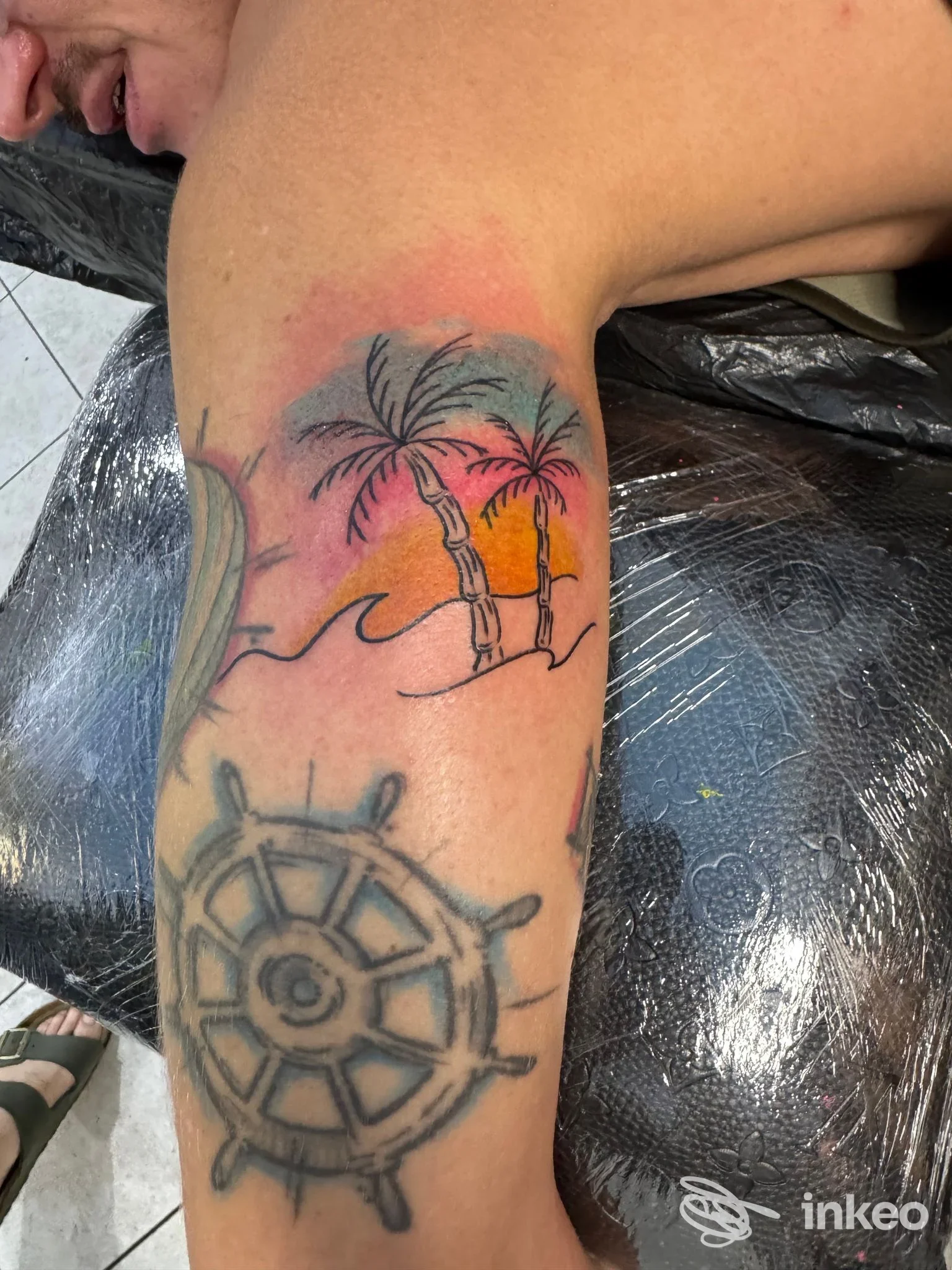 Tatuaggio con palme e tramonto sul bicipite, fotografia del lavoro eseguito da Arde Roma Tattoo a Roma.