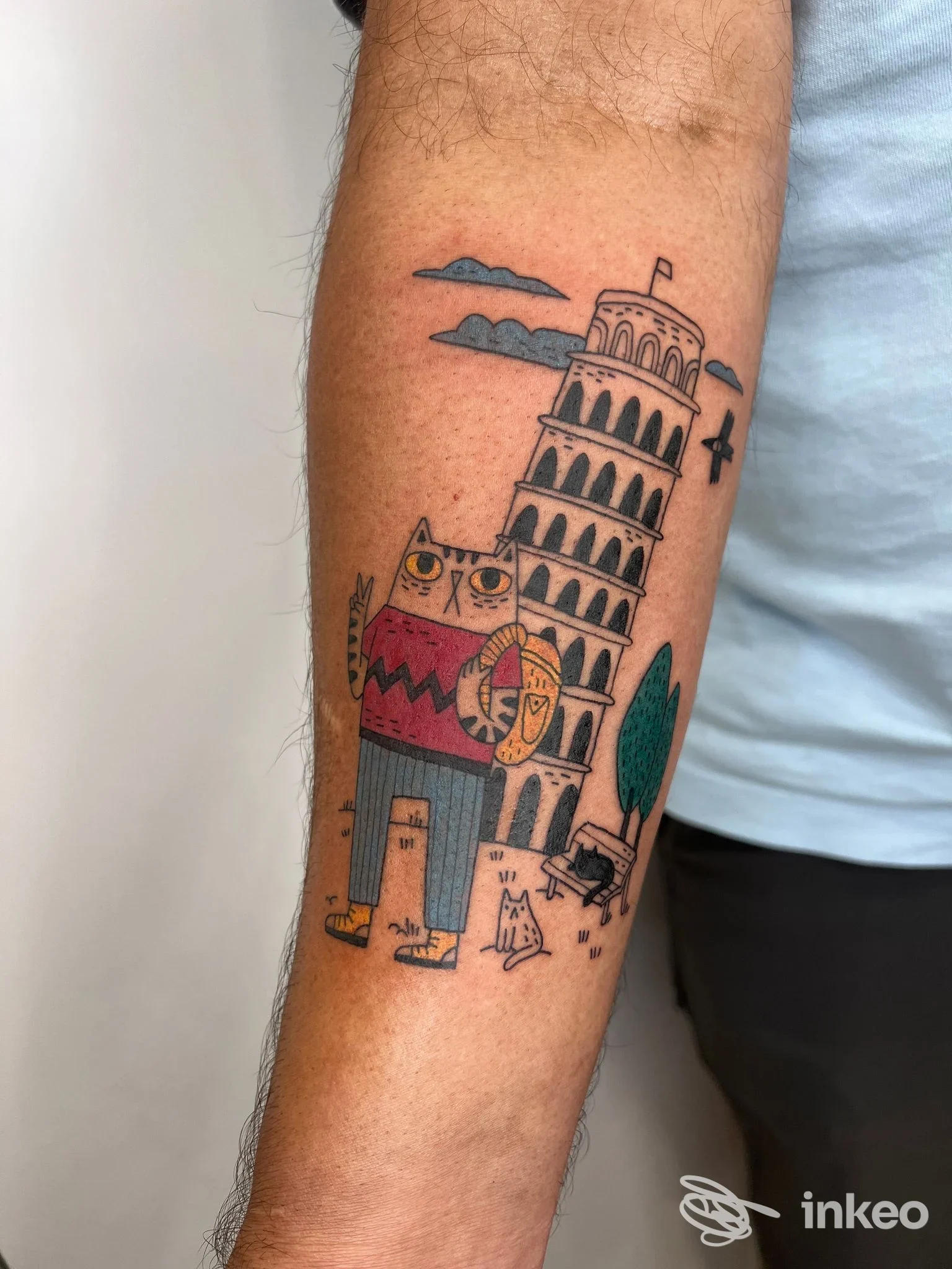 Tatuaggio colorato su avambraccio con un gatto stilizzato e la Torre di Pisa, foto da Area Industriale Tattoo Roma, Roma.
