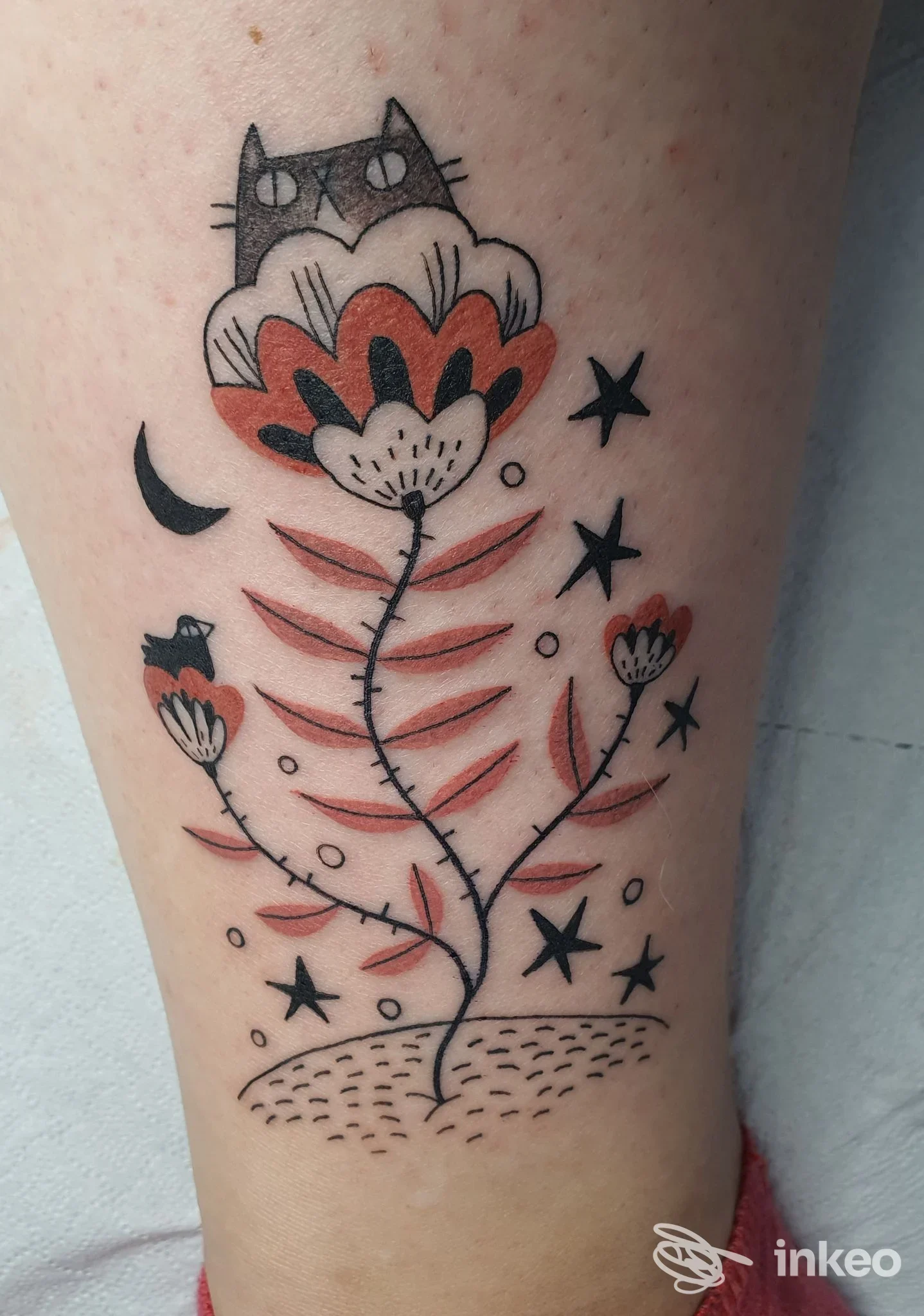 Tatuaggio su pelle a Roma: fiore stilizzato con piccolo gatto, stelle e mezzaluna. Scatto fornito da Area Industriale Tattoo Roma.