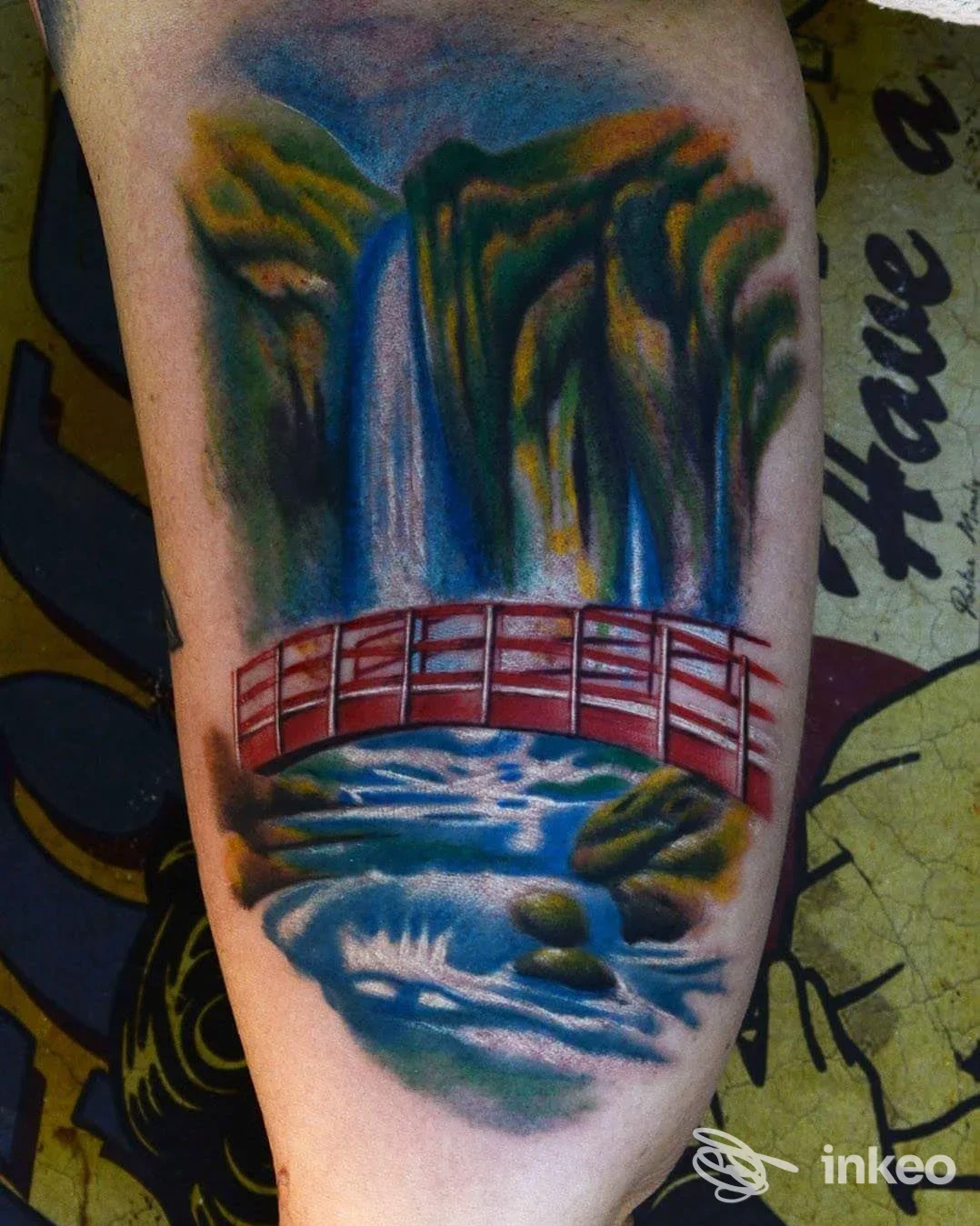 Tatuaggio a colori di paesaggio con cascata e ponte rosso, eseguito su pelle. Black Dragon Tattoo Roma, Roma.