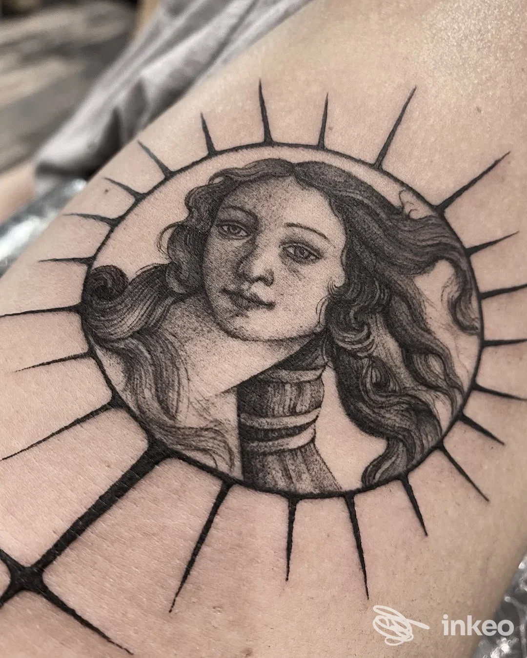 Ritratto tatuato in bianco e nero dentro un cerchio con raggi sul braccio. Bloody Anvil Tattoo, Roma.