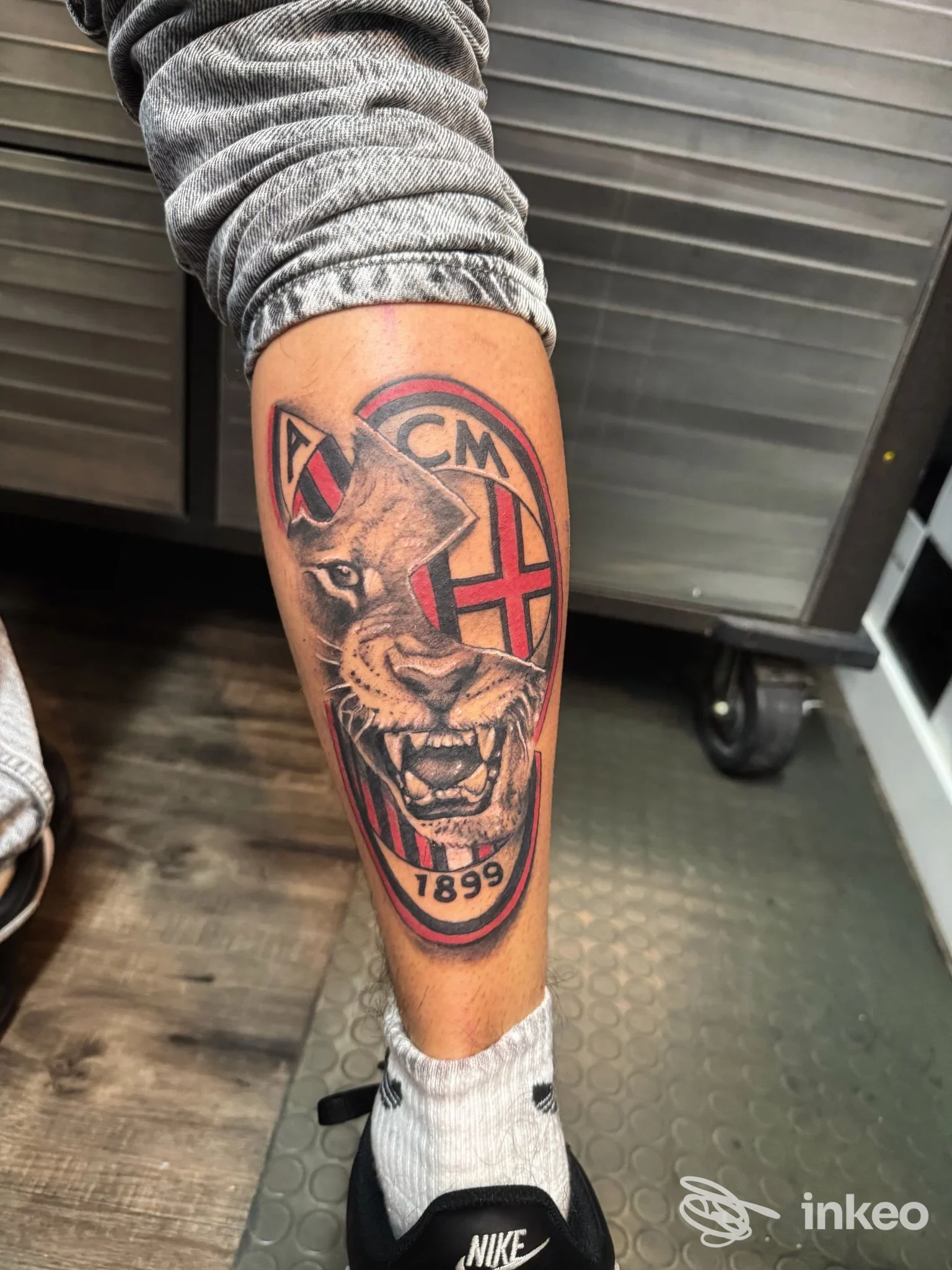 Tatuaggio sul polpaccio con volto di felino e simboli 'ACM' e '1899', Cajeta Ink Tatuaggi, Gaeta.