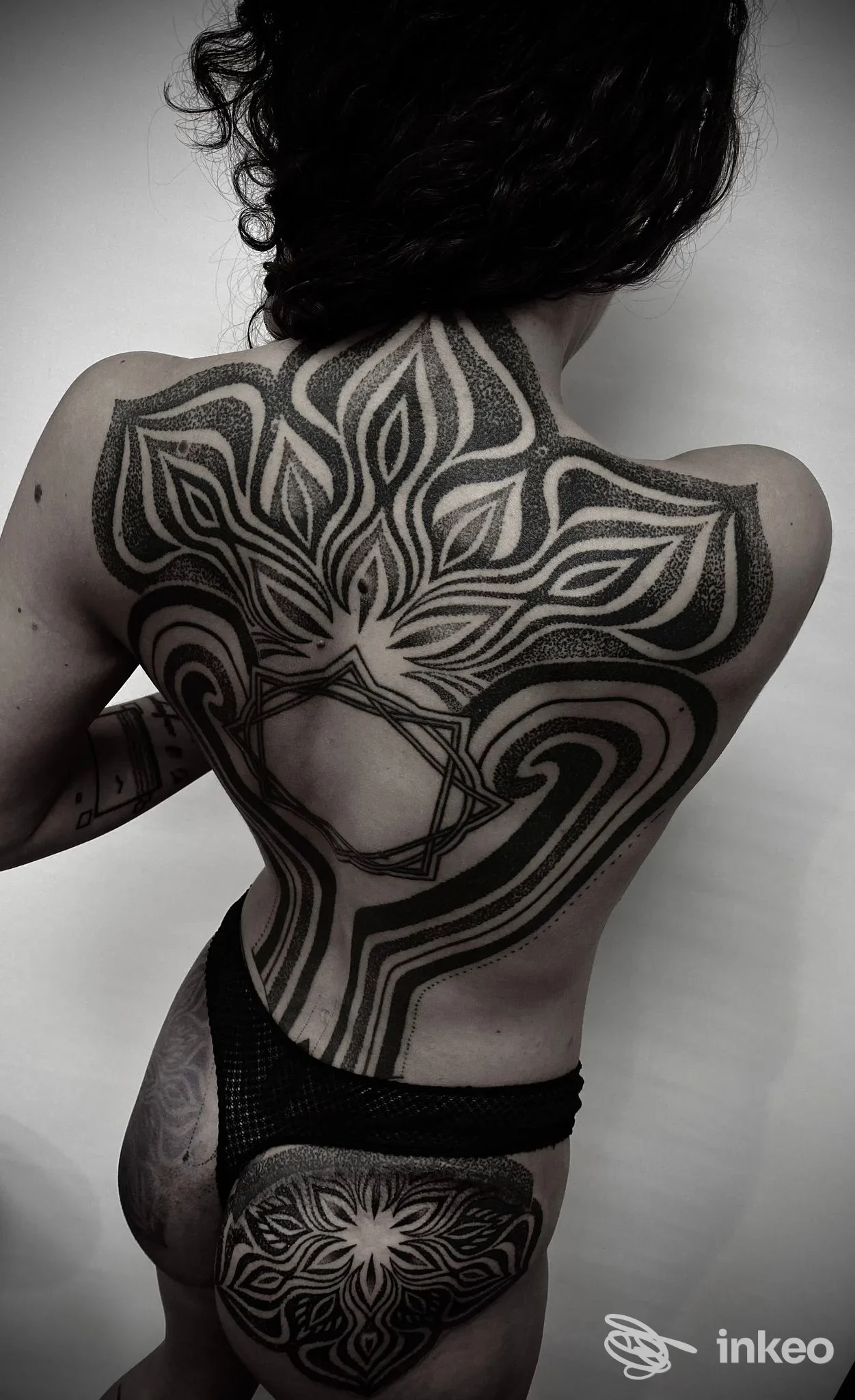 Ampia copertura dorsale in stile geometrico/ornamentale realizzata da Carnale Tattoo a Roma, vista di tre quarti da dietro.