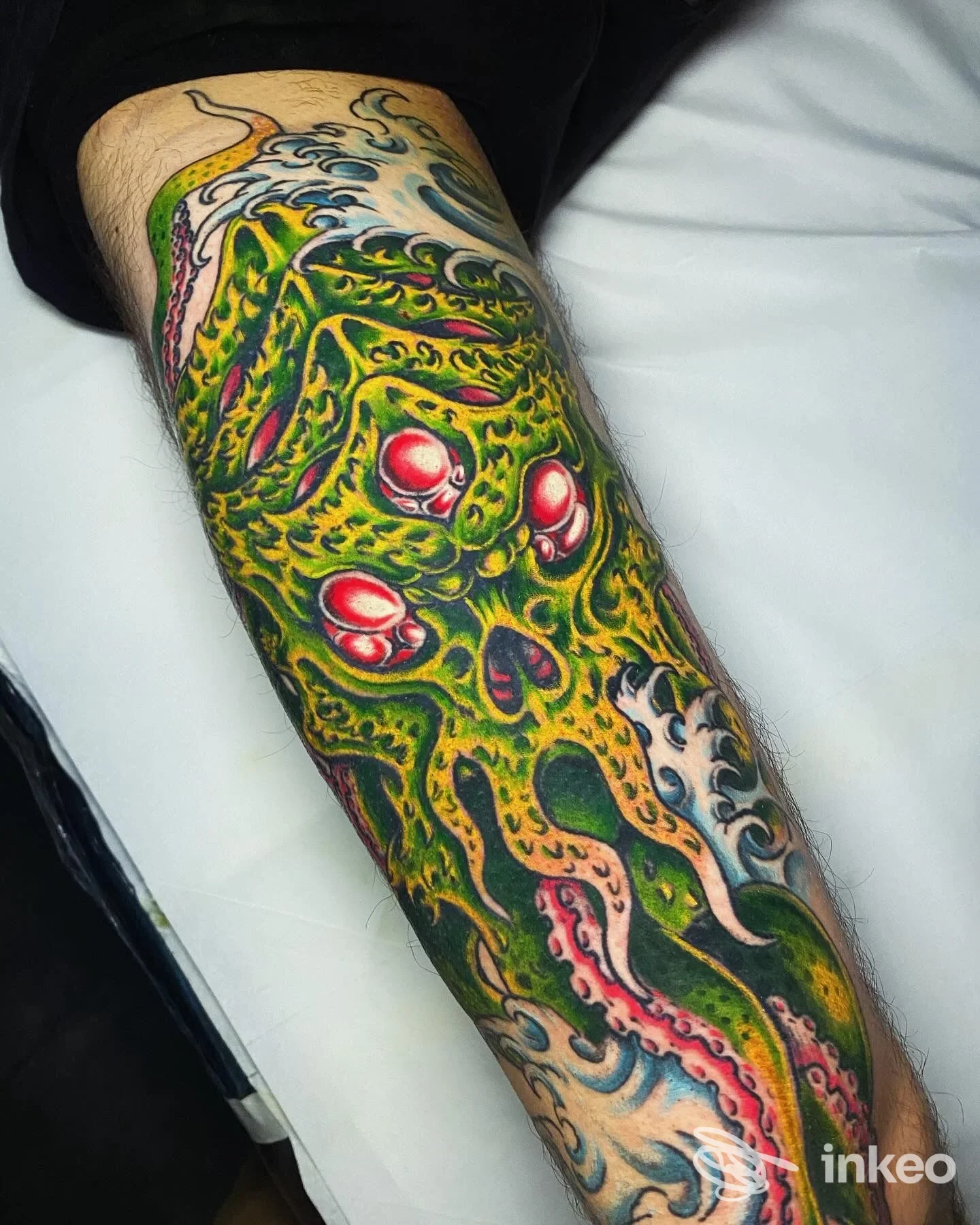 Grande tatuaggio colorato su avambraccio raffigurante creatura tentacolare verde con occhi rossi. Flower Power - Tattoo & Piercing, Roma