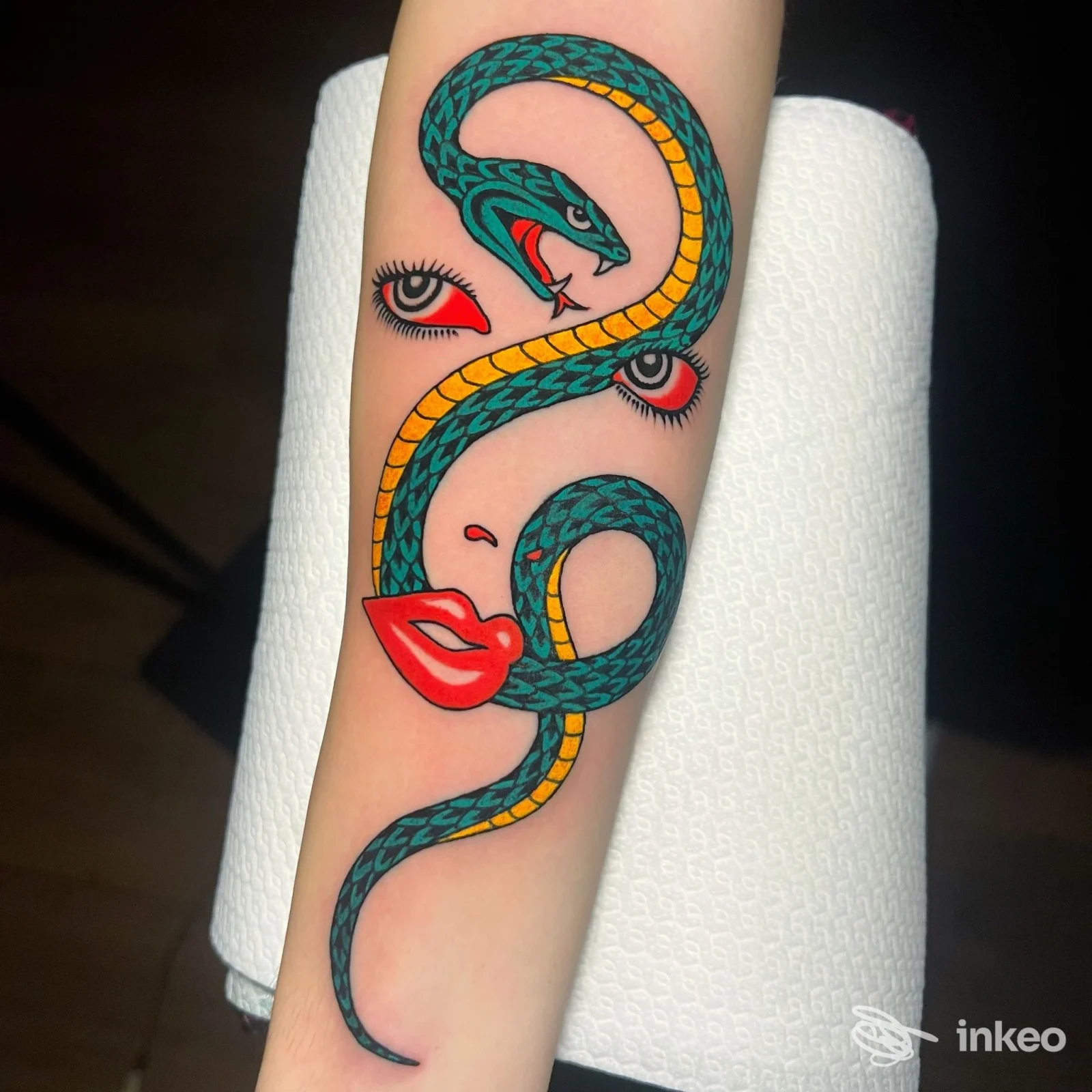 Tatuaggio su avambraccio con serpente verde e dettagli di volto stilizzato, foto condivisa da Gold Blood Tattoo Trastevere a Roma.