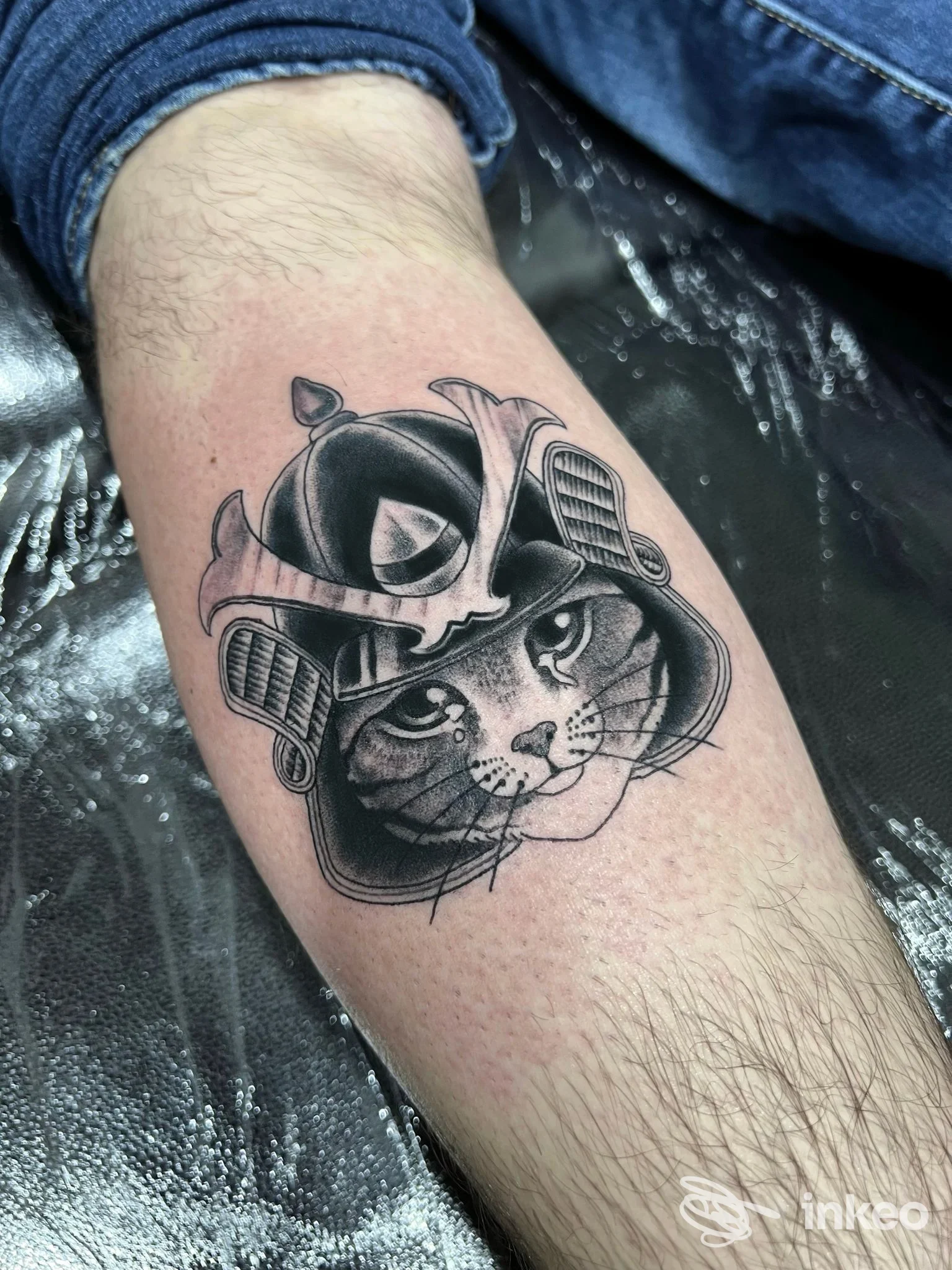 Tatuaggio in nero e grigio di una testa di gatto con elmo sull'avambraccio, scatto da Gold Blood Tattoo Trastevere a Roma.