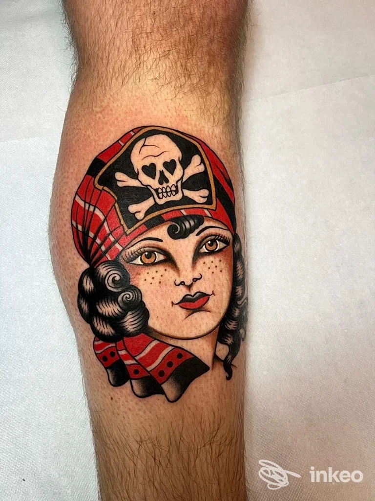 Tatuaggio tradizionale su polpaccio di Ink For Blood Tattoo & Piercing, Roma: volto femminile con foulard rosso e teschio.