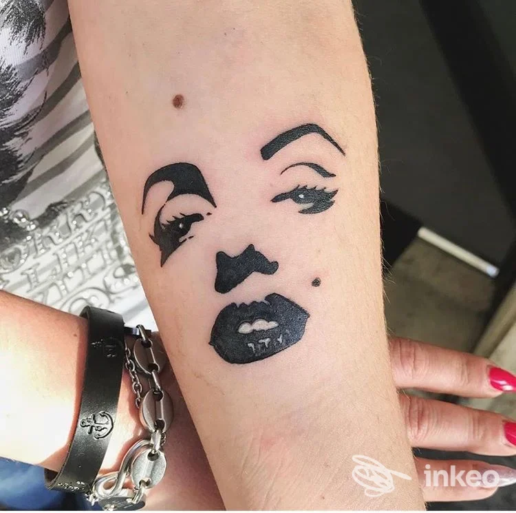 Tatuaggio in stile blackwork di un volto stilizzato sull'avambraccio, foto fornita da LaSux Tattoo a Roma.