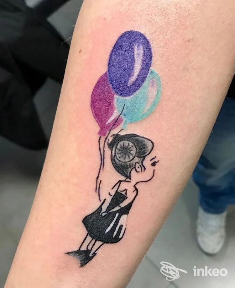 Tatuaggio sull'avambraccio di una bambina stilizzata con tre palloncini colorati, foto fornita da LaSux Tattoo, Roma.