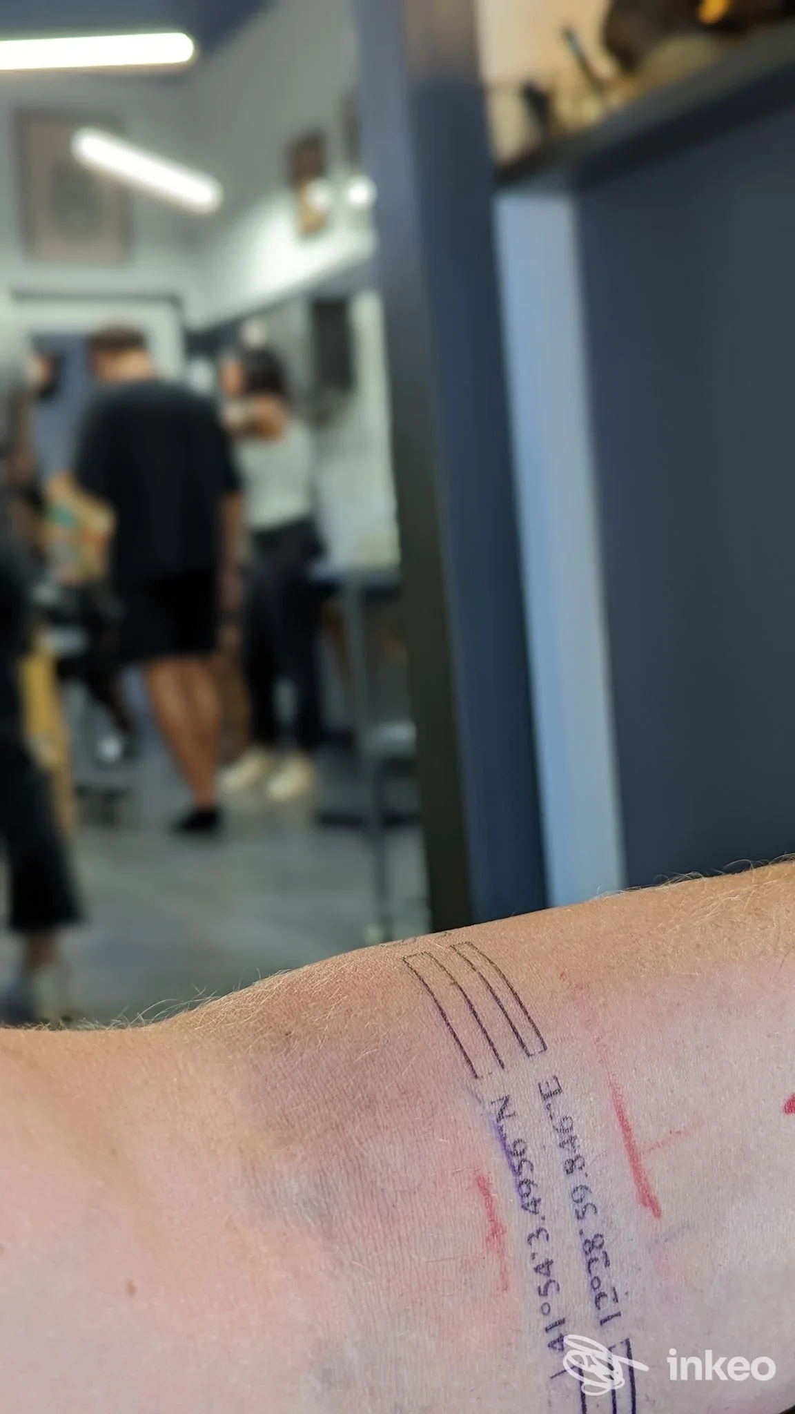 Primo piano di un avambraccio con piccolo tatuaggio a linee e numeri, scattato in studio; Mano Santa Tattoo, Roma.