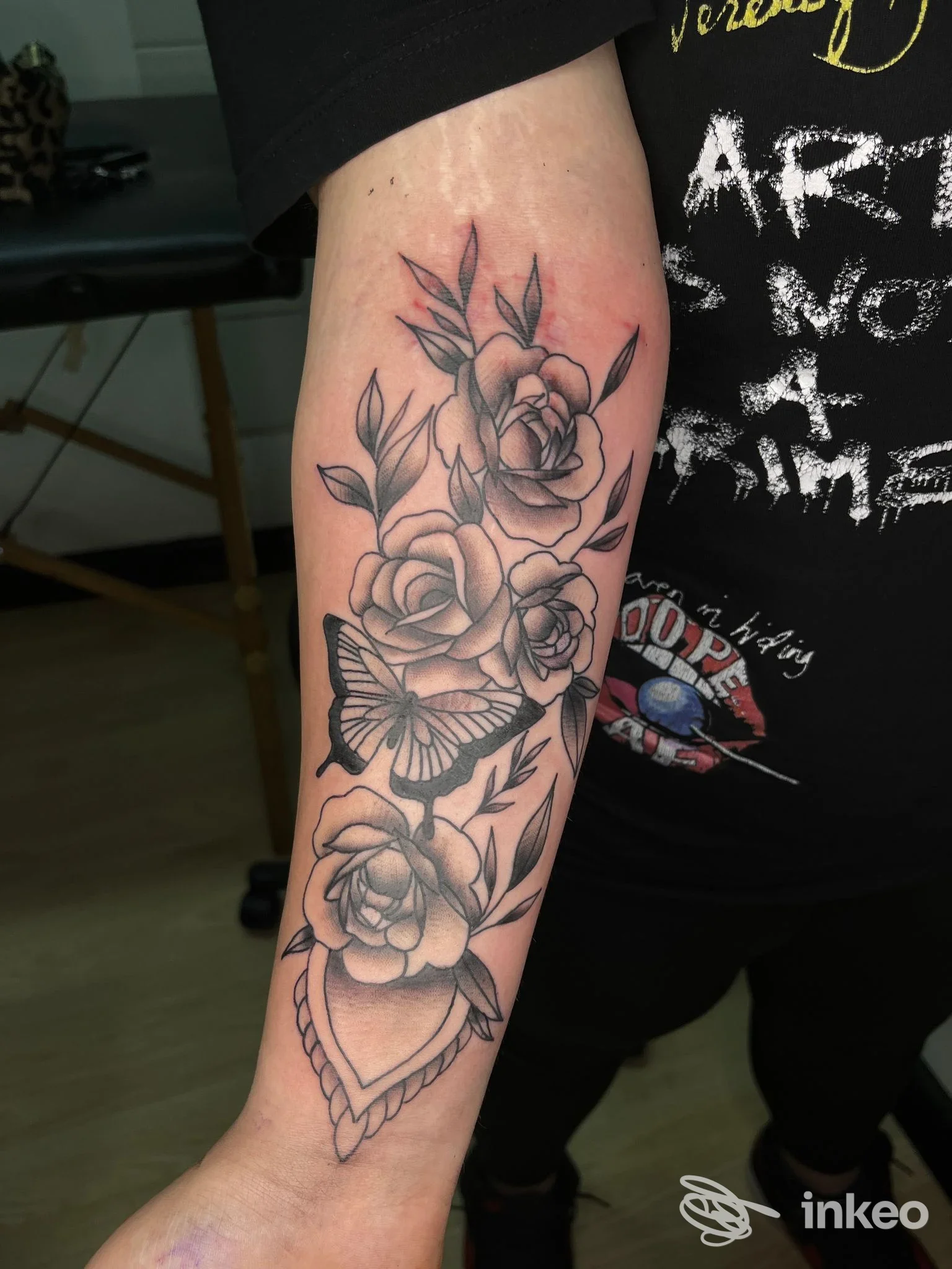 Avambraccio tatuato con rose, foglie e farfalla in nero/grigio, lavoro eseguito da Mattia kein tattoo a Cisterna di Latina.