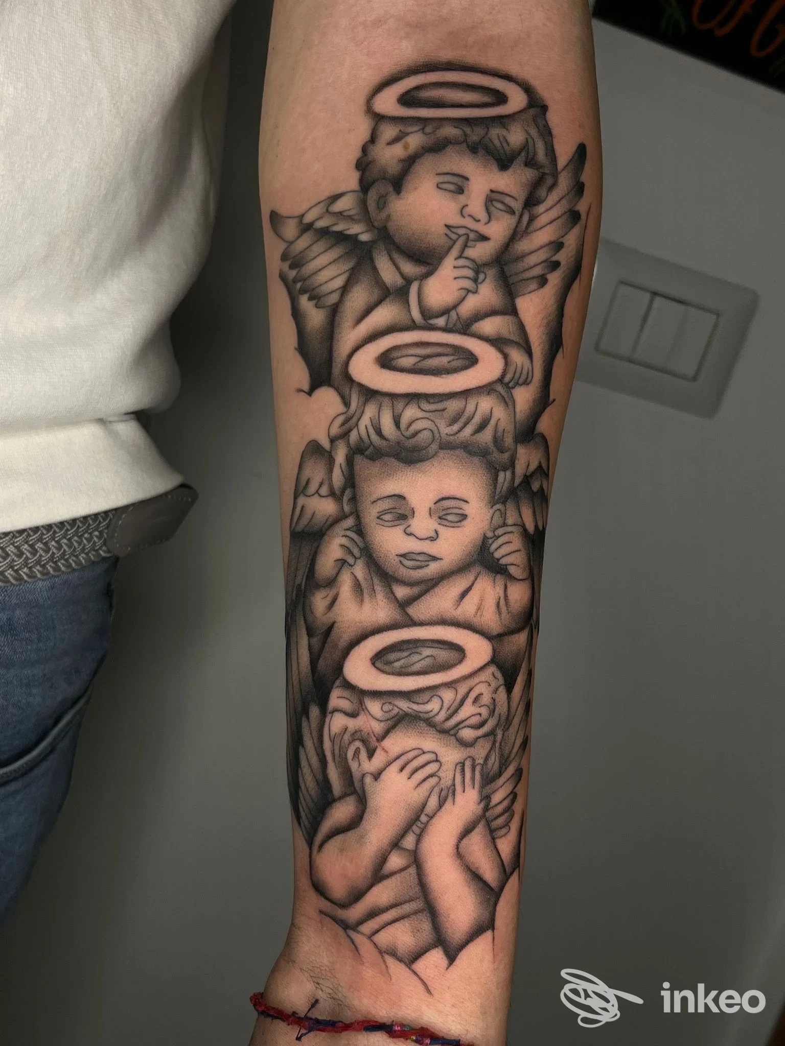 Tatuaggio in bianco e nero su avambraccio con tre angeli/cherubini. Mattia kein tattoo, Cisterna di Latina.