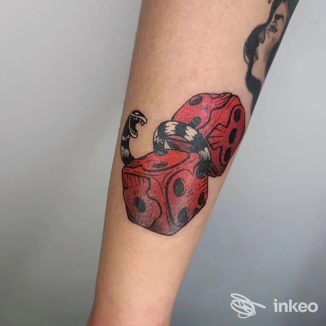 Tatuaggio sull'avambraccio con due dadi rossi e un serpente nero, Jay Lester Tattoo Trastevere, Roma.