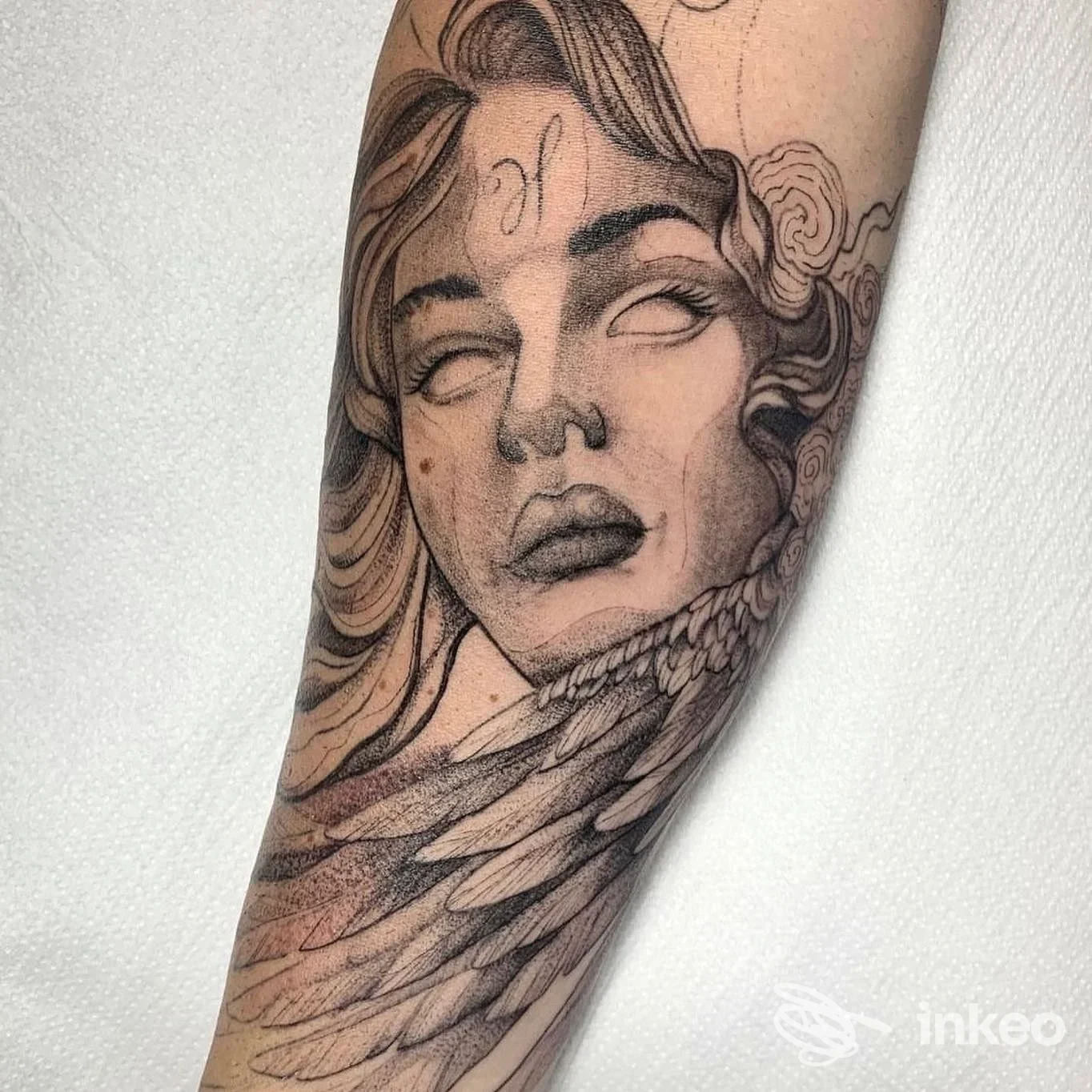 Tatuaggio su avambraccio di volto femminile stilizzato con piume, Mad Whale Tattoo Studio, Roma.