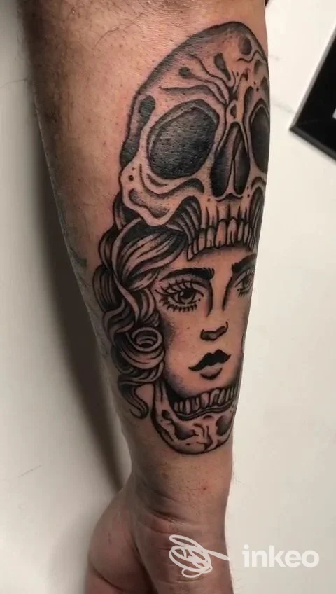 Tatuaggio nero e grigio su avambraccio con teschio che si sovrappone a volto femminile, Mastro Tattoo, Roma.