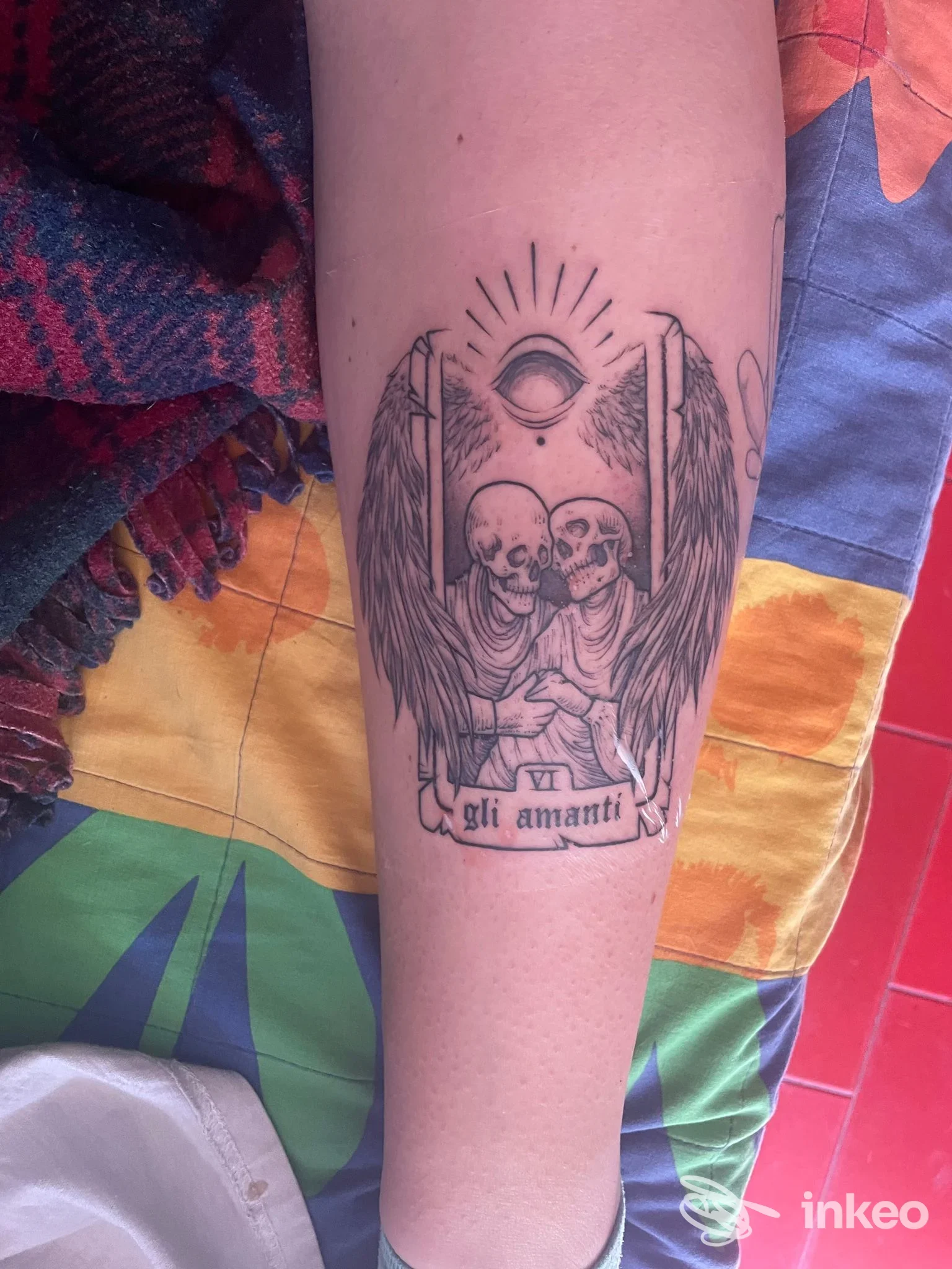 Tatuaggio in bianco e nero su avambraccio con due scheletri abbracciati e ali, Old Gate Tattoo, Roma.