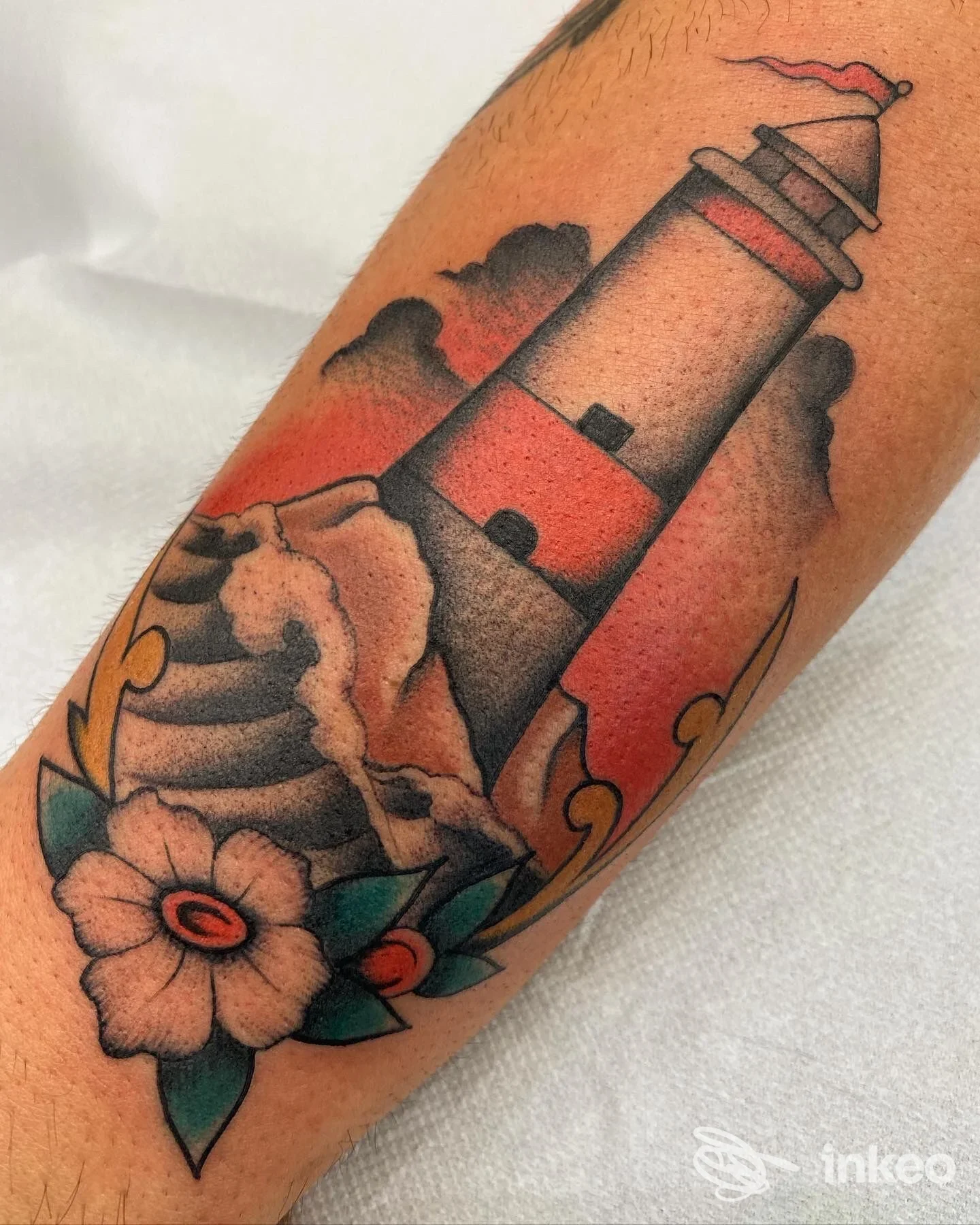 Tatuaggio su avambraccio con faro tradizionale, onde e fiori — No Rulez tattoo, Marino.
