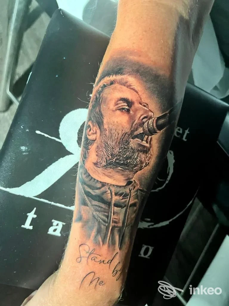 Tatuaggio realistico di un volto che canta sul lato interno dell'avambraccio, foto fornita da RED CARPET TATTOO - Manuel Conte, Roma.