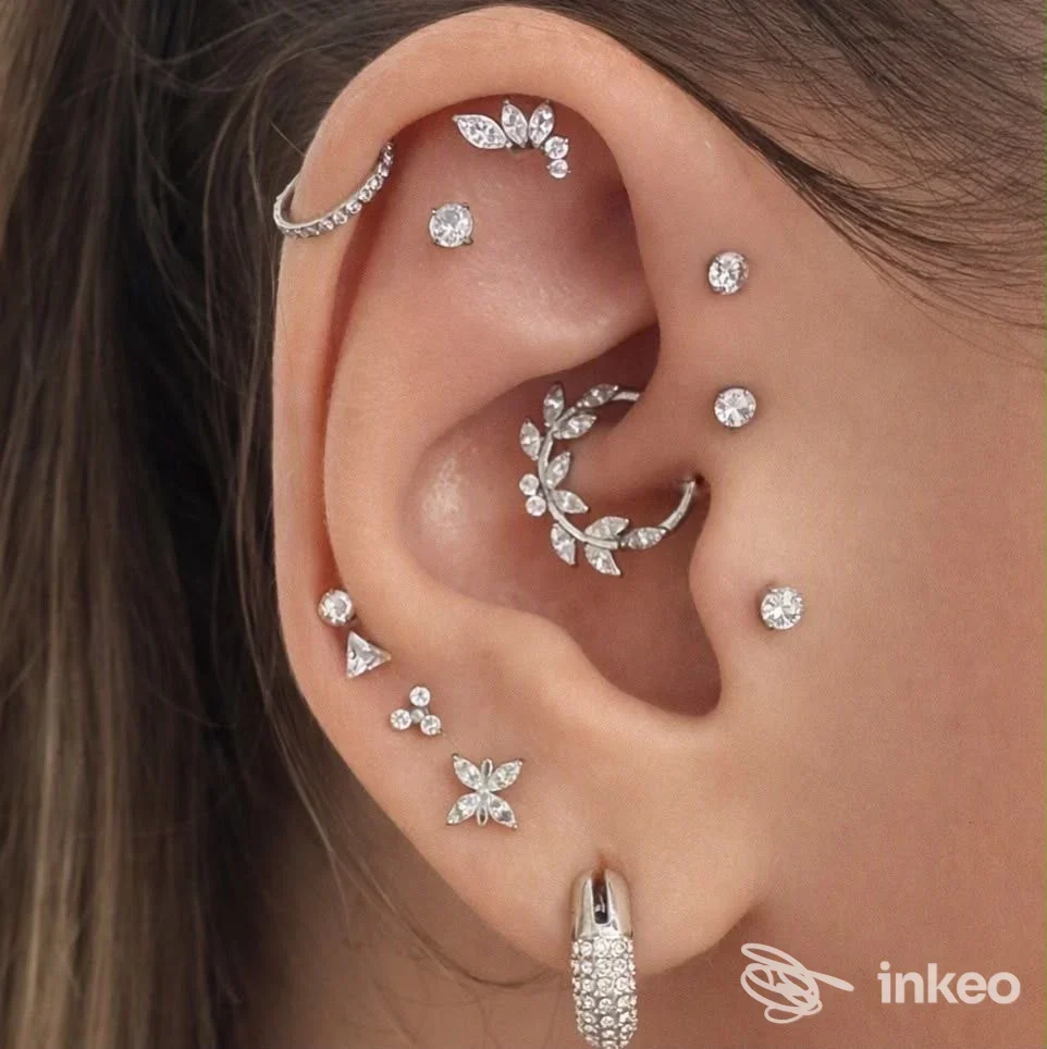Primo piano di un orecchio con multipli piercing e gioielli in argento, immagine fornita da Resilience tattoo studio, Roma.