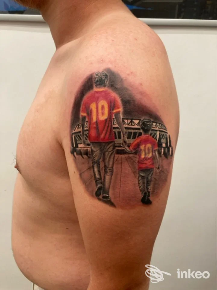 Tatuaggio sul braccio superiore che raffigura due figure di spalle con maglie rosse e il numero 10, Old Store Tattoo, Roma.