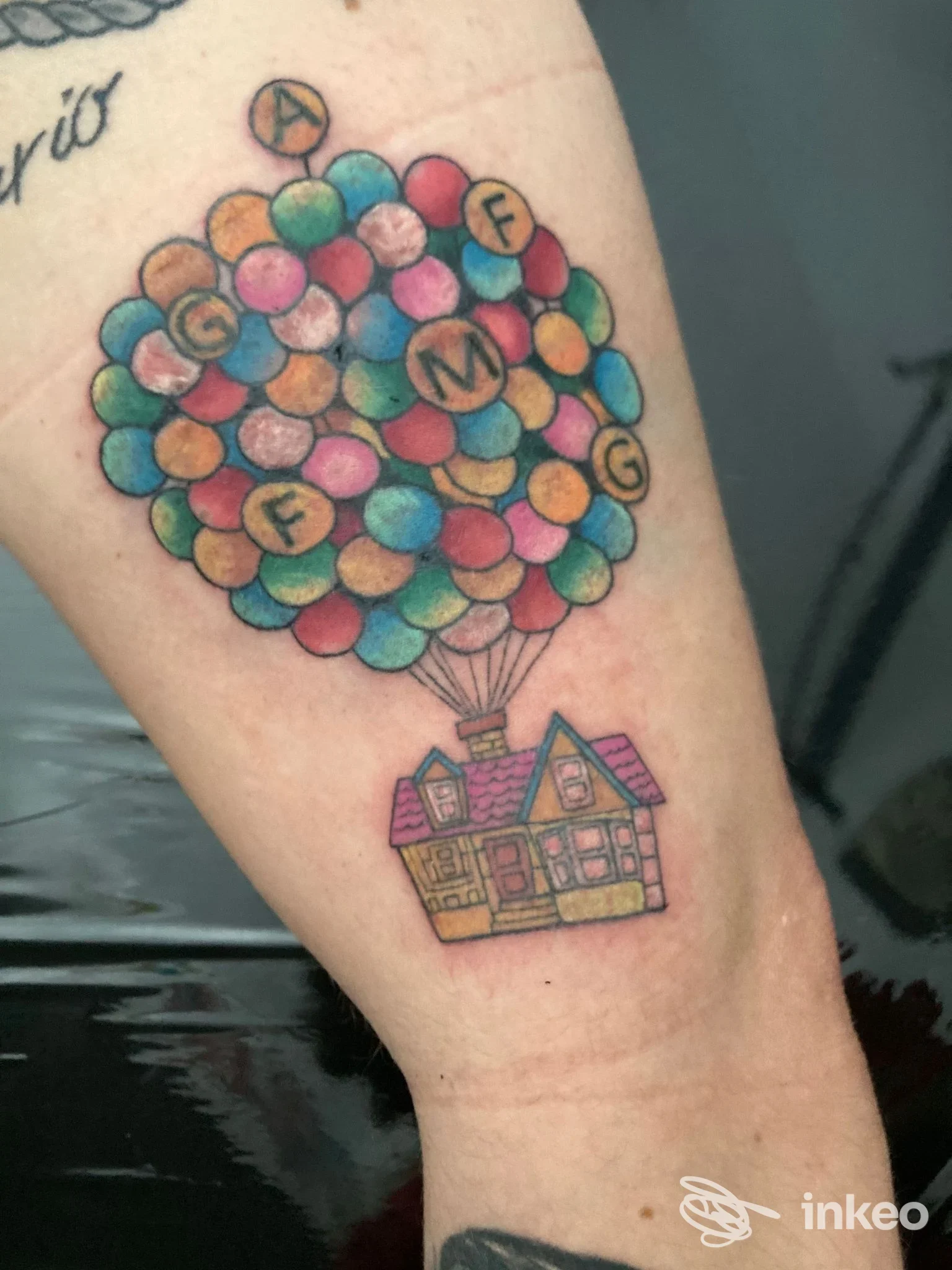 Tatuaggio su avambraccio raffigurante una casetta sollevata da molti palloncini colorati, scatto fornito da Old Store Tattoo, Roma.