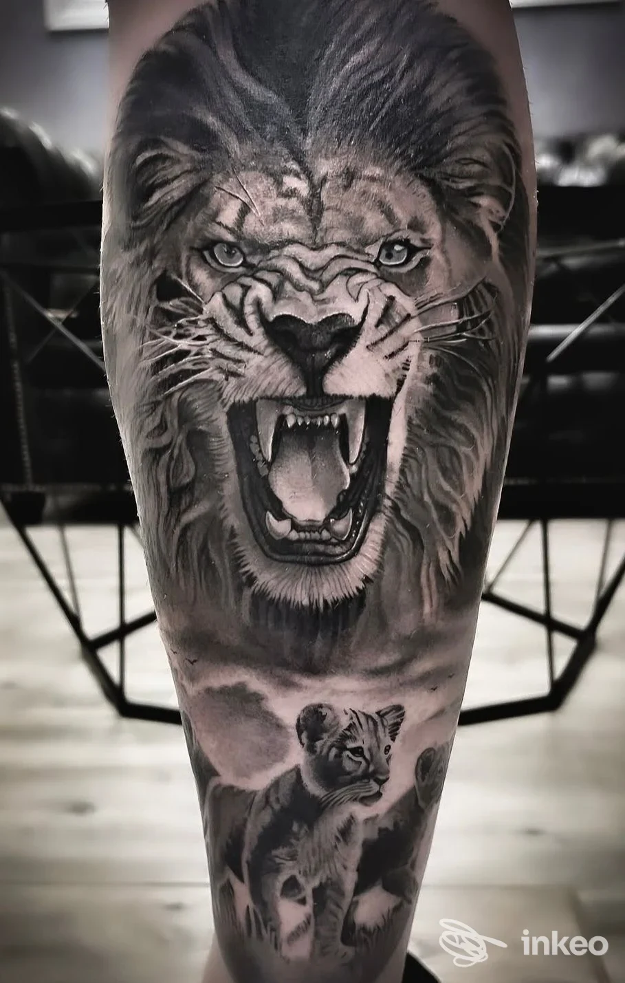 Tatuaggio realistico in bianco e nero di un leone ruggente con cuccioli sul polpaccio, Royal Queen Tattoo, Cisterna di Latina.