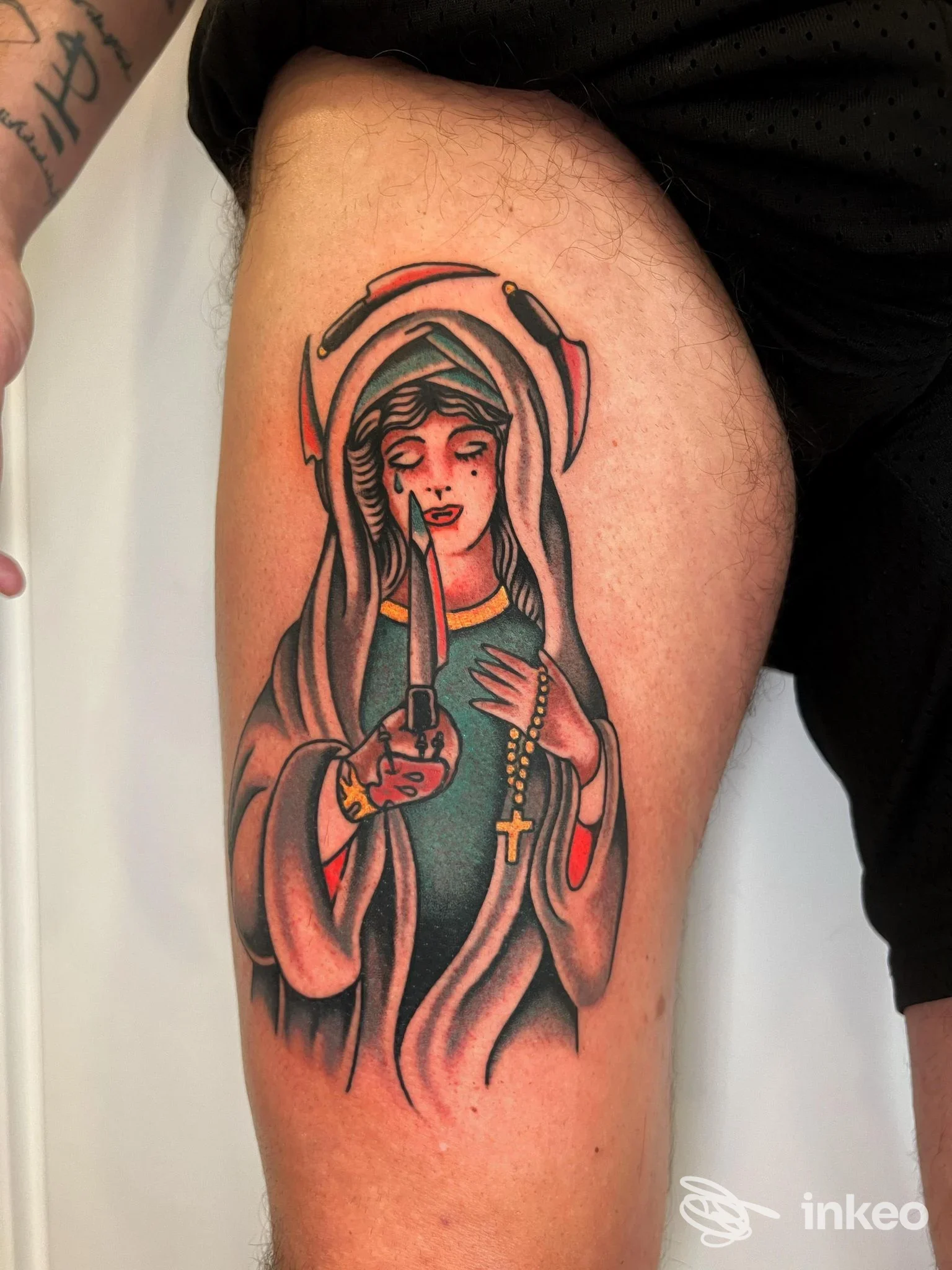 Tatuaggio colorato su coscia raffigurante figura velata con rosario e pugnale, scatto di RustyDaggerTattoo, Roma.