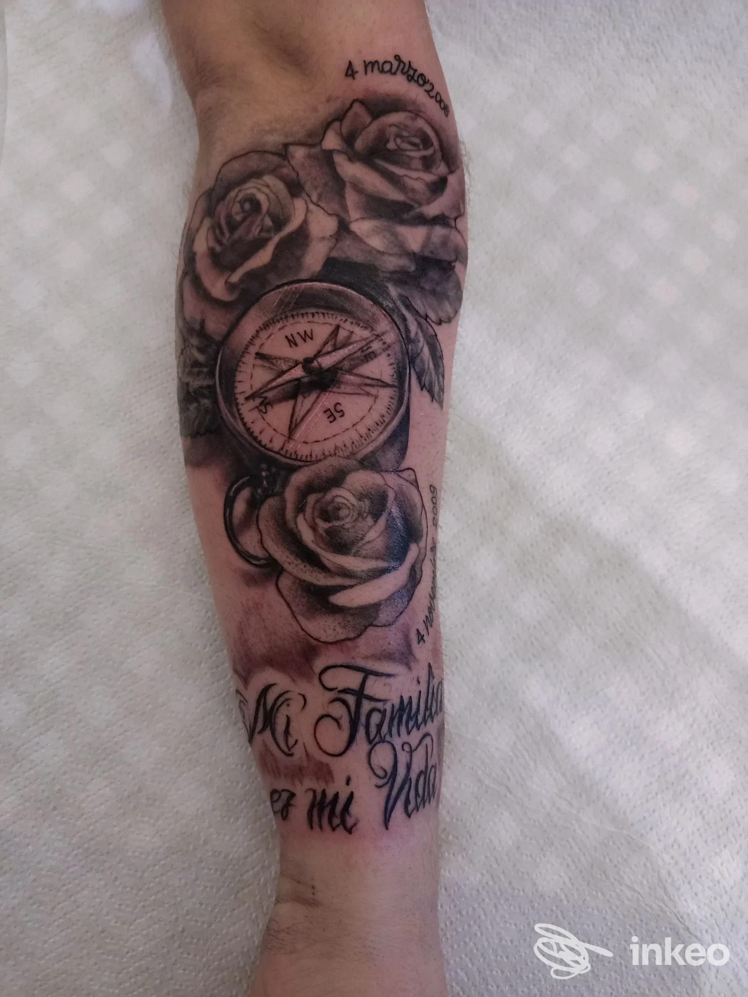 Tatuaggio avambraccio con bussola, rose e scritte in bianco e nero realizzato da SCRIPTA MANENT TATTOO a Roma, dettaglio frontale.
