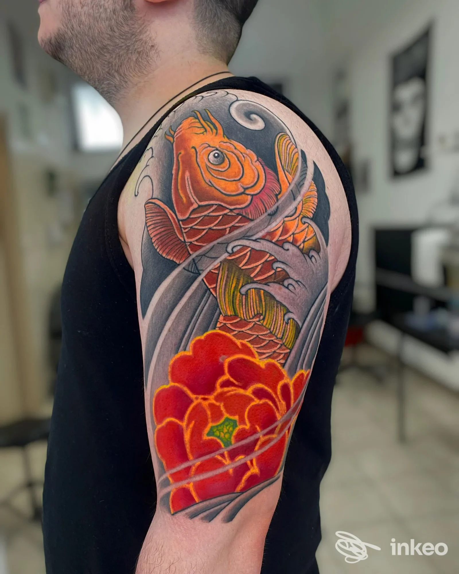 Tatuaggio a colori (koi e fiore) su spalla e braccio superiore, foto scattata in studio Santa Suerte Tattoo Studio, Roma.