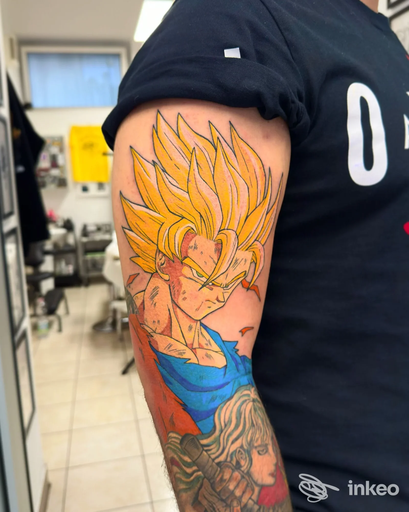 Tatuaggio stile anime sul braccio superiore realizzato da Santa Suerte Tattoo Studio, Roma: personaggio con capelli gialli e dettagli blu e rossi.