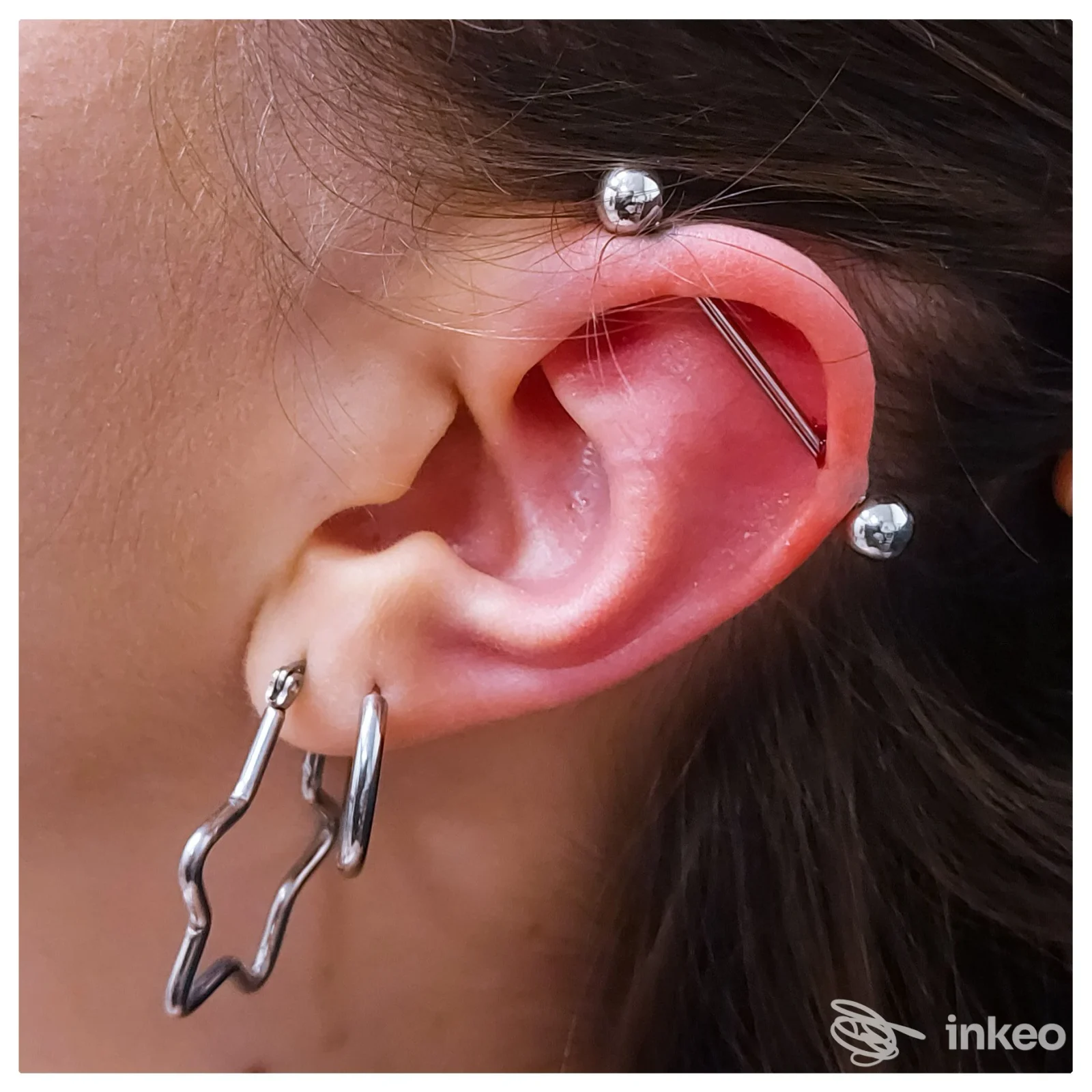 Primo piano di orecchio con industrial e più piercing, Rated R Tattoo Roma, Roma.