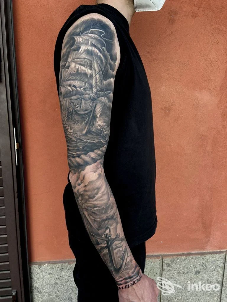 Manica tatuata in bianco e nero con grande nave e onde sul braccio destro, foto inviata da SMEL Tattoos - Colleferro.