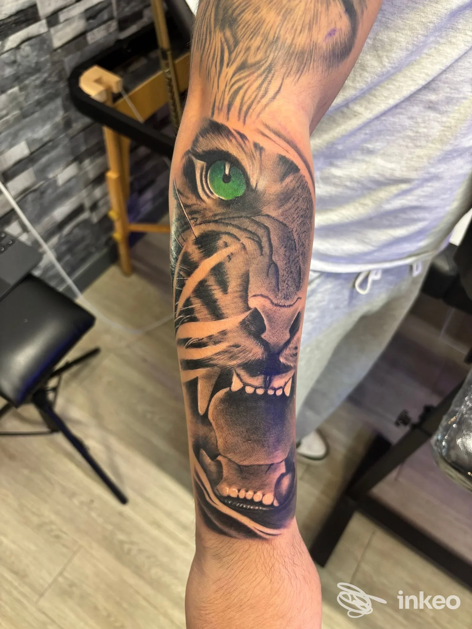 Tatuaggio realistico di una tigre con occhio verde sull'avambraccio, foto fornita da T'n'T Ink tattoo studio, Nepi.