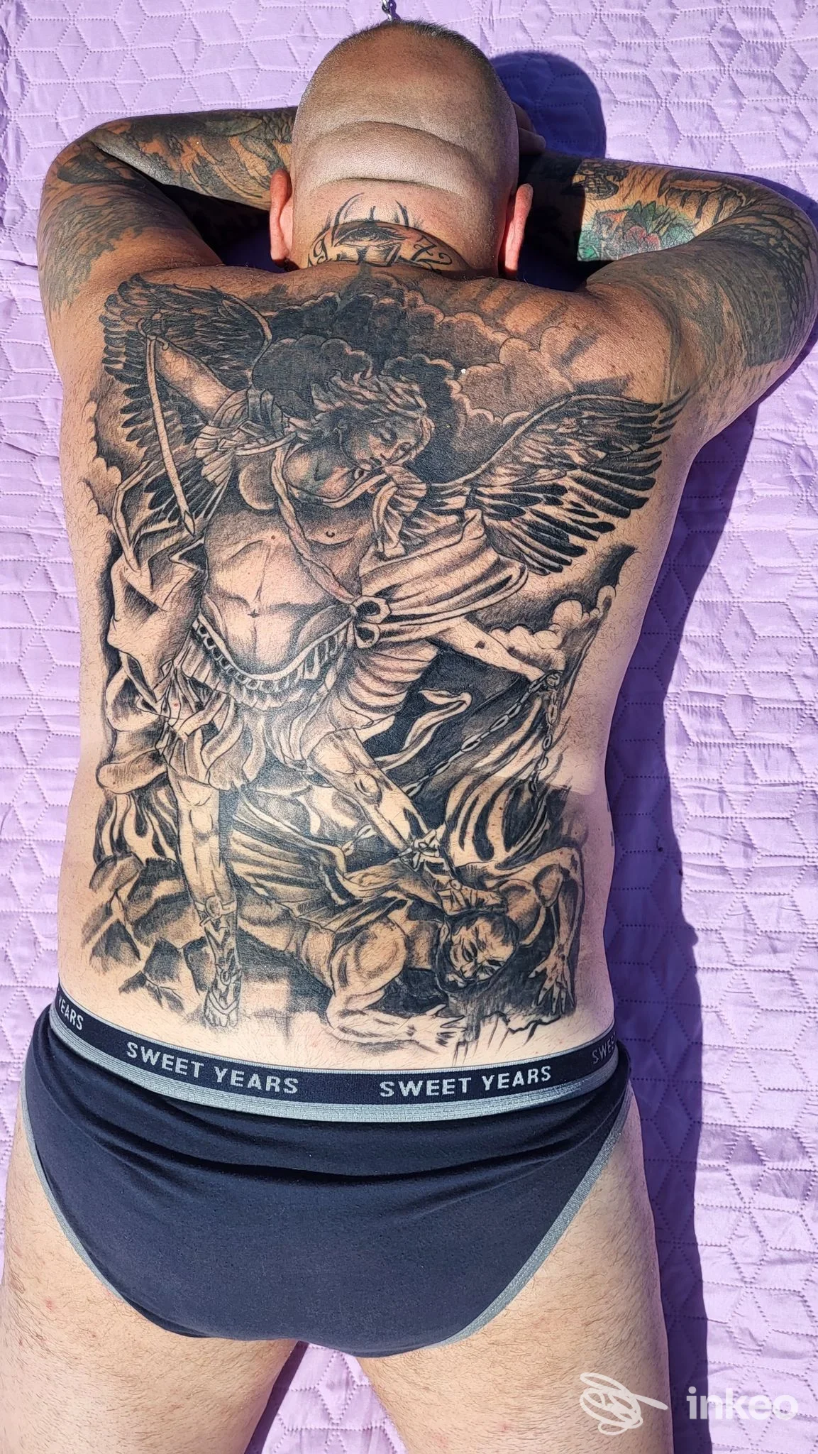 Ampio tatuaggio black&grey a figura centrale che ricopre l'intera schiena di un uomo sdraiato; immagine fornita da Tatto Matto Roma, Roma.
