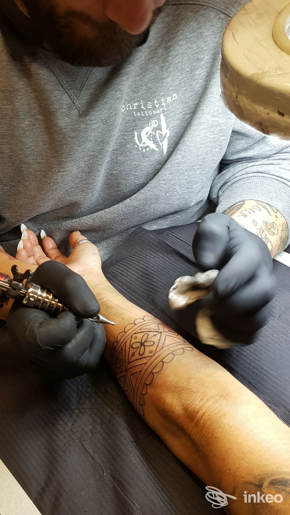 Tatuaggio in corso sull'avambraccio, artista Christian al lavoro nello studio di Fiumicino.