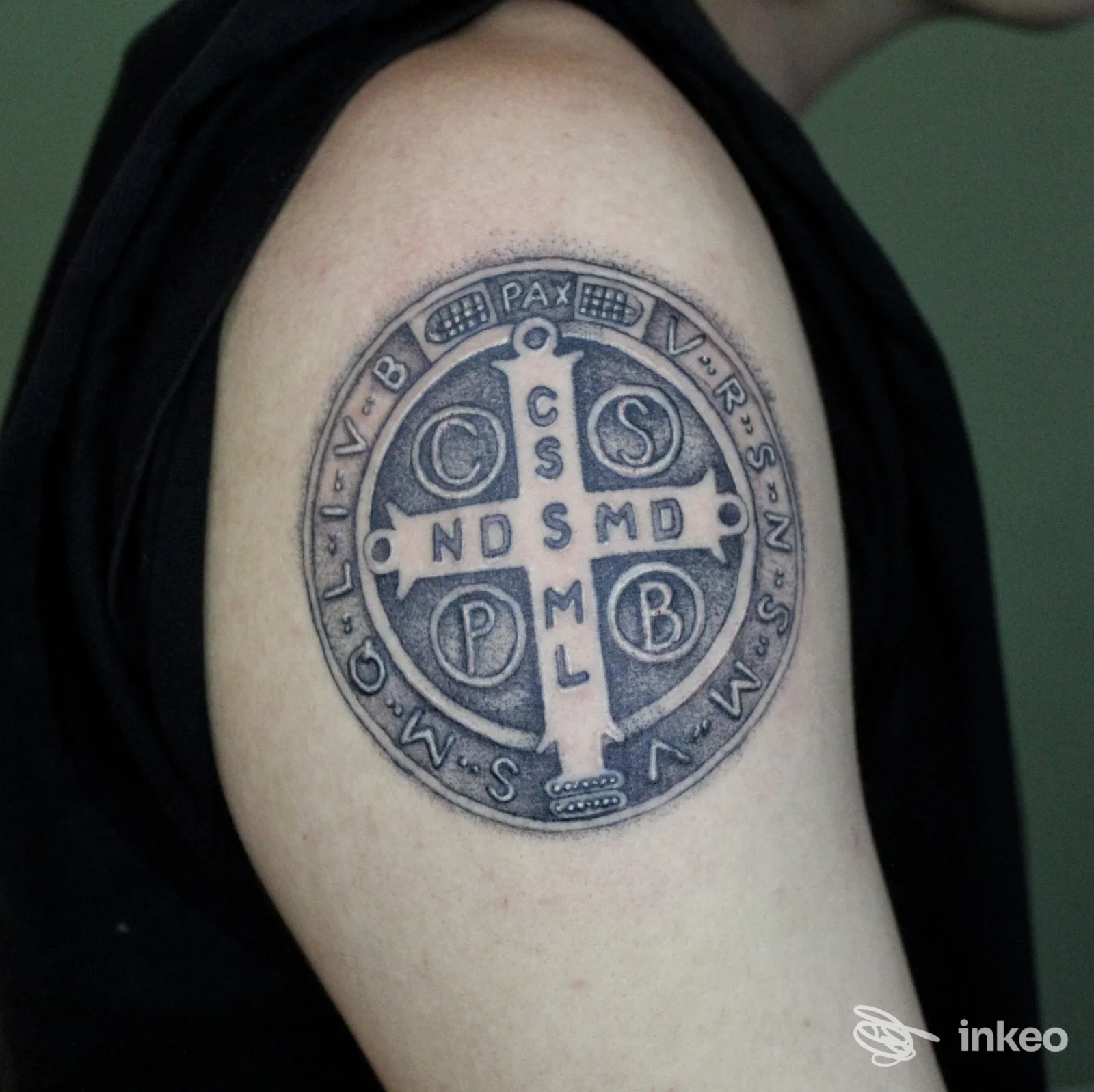 Tatuaggio della Croce di San Benedetto sul braccio superiore, realizzato da Seahorse Tattoo a Roma.