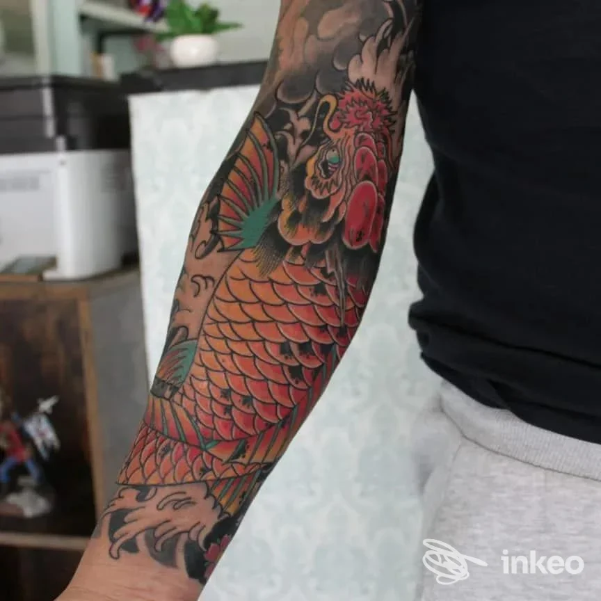 Avambraccio tatuato a manica con una carpa koi dai toni arancioni e rossi e onde stilizzate, foto fornita da Seahorse Tattoo, Roma.
