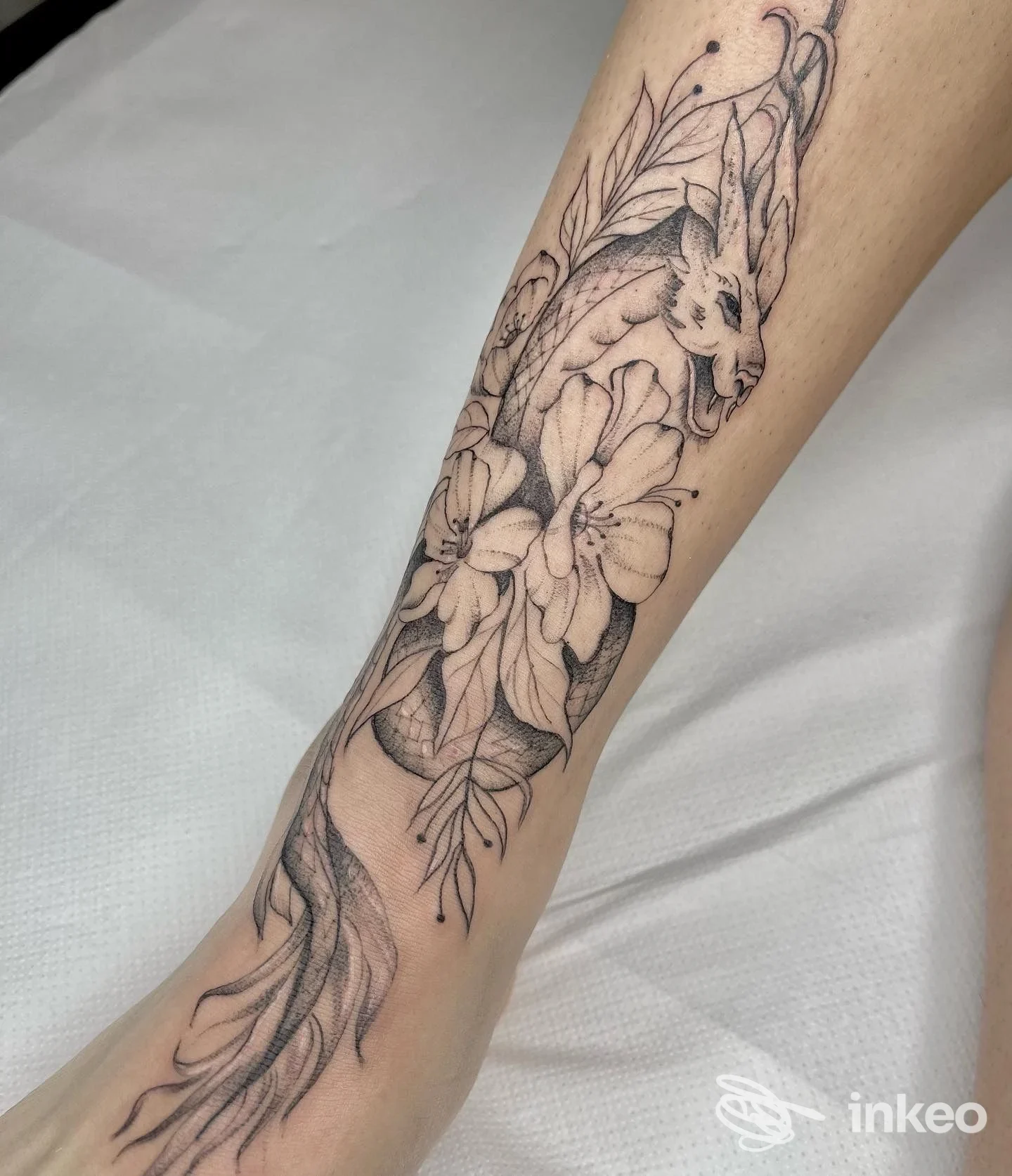 Tatuaggio in bianco e nero con fiori e testa di animale sul lato interno dell'avambraccio, lavoro eseguito da Tattoo & Sketch Studio a Fiumicino.