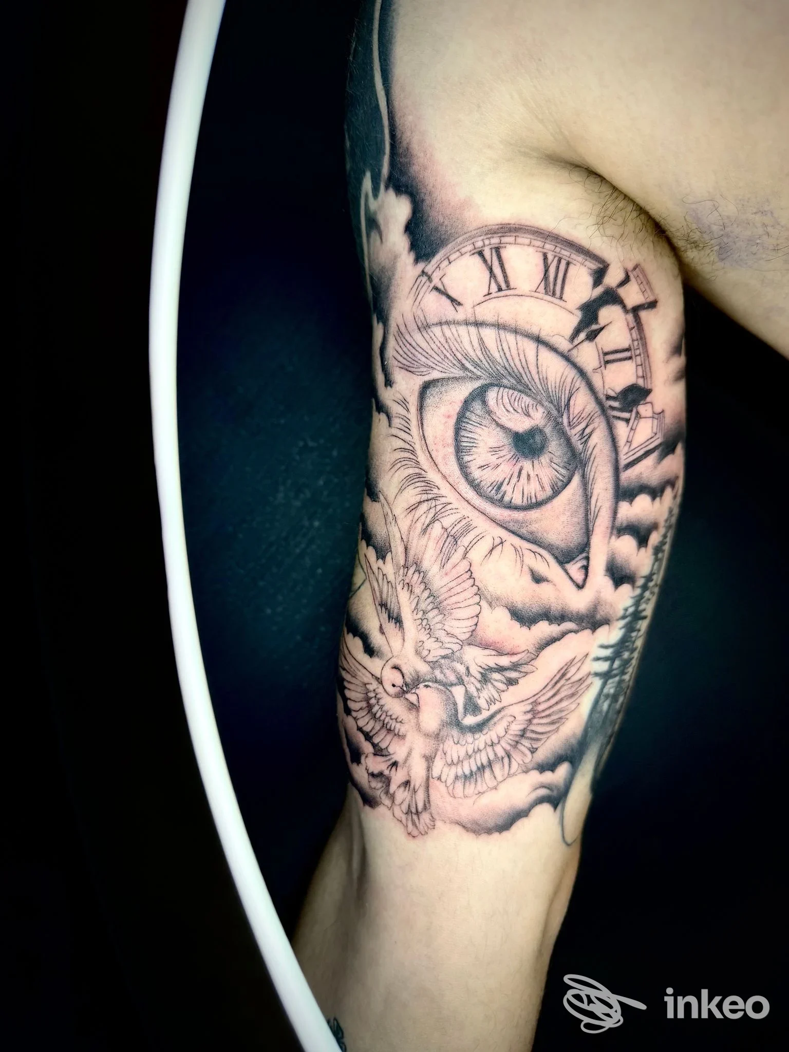 Tatuaggio realistico sull'interno braccio con occhio, orologio e colombe, servizio per Tattoo Giordano a Velletri.