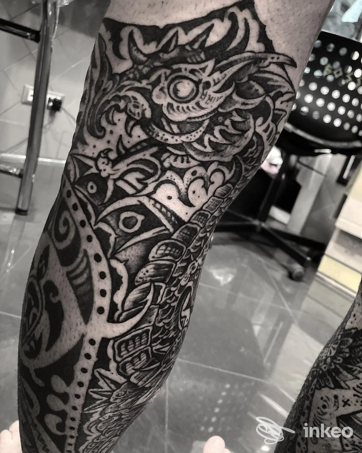 Dettaglio di tatuaggio in bianco e nero sul polpaccio con motivi ornamentali e figure stilizzate, fotografia scattata nello studio Yama Tattoo a Roma.