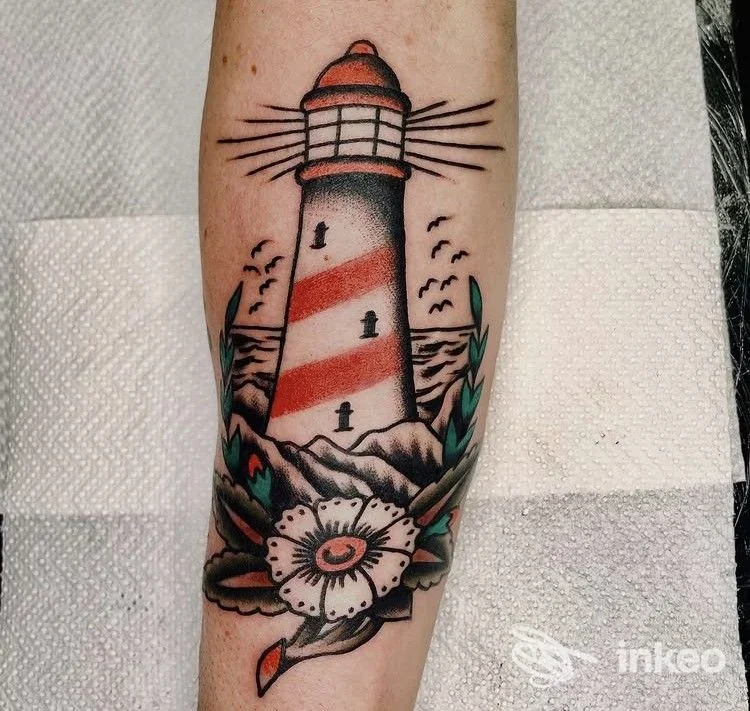 Tatuaggio realizzato da Yama Tattoo a Roma: faro in stile old school con onde, gabbiani, foglie e fiore colorato sul lato interno dell'avambraccio.