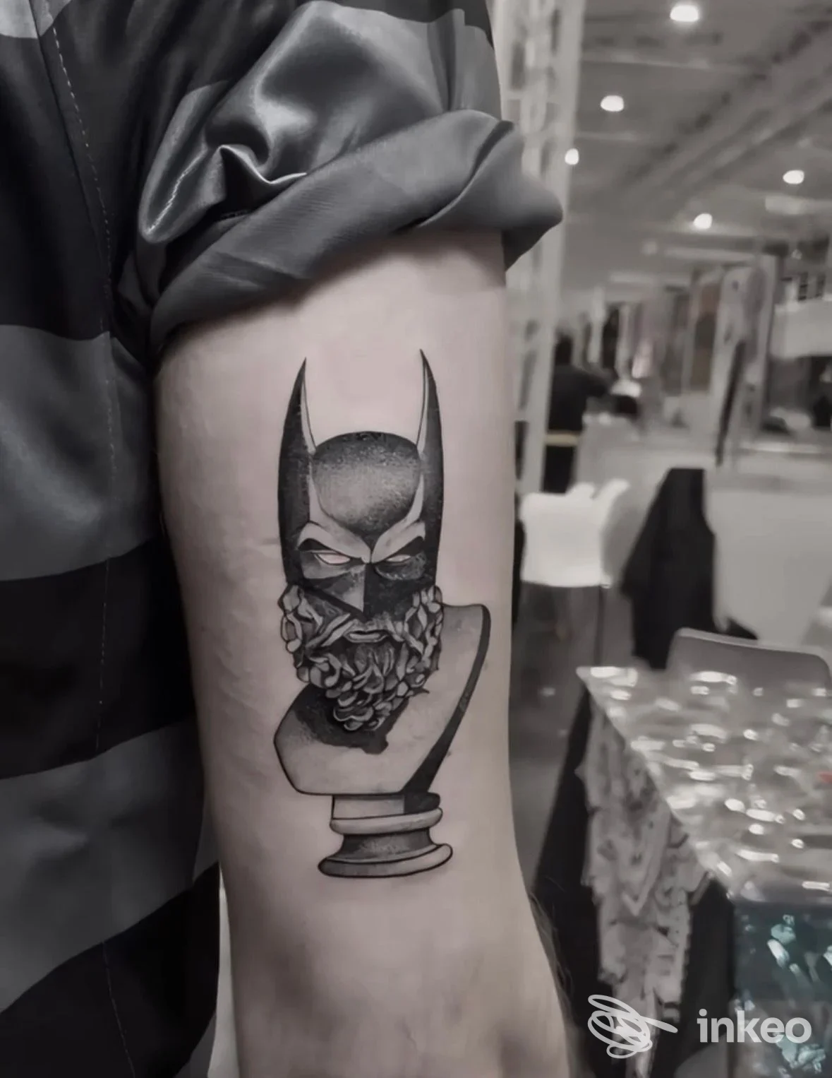 Tattoo su pelle: testa di Batman stilizzata impressa sull'avambraccio, visuale nitida su una base a forma di busto. Foto scattata nello studio, braccio come soggetto principale.