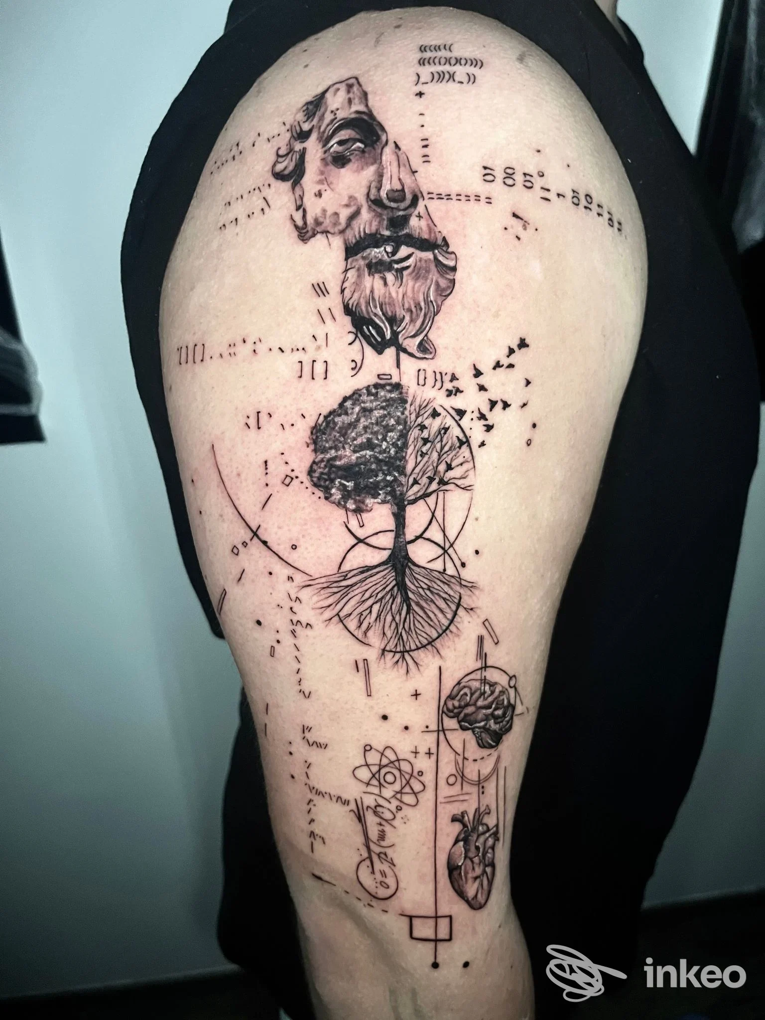 Tatuaggio su alto braccio con volti stilizzati, albero con radici e simboli geometrici — Arte su pelle, Formia.