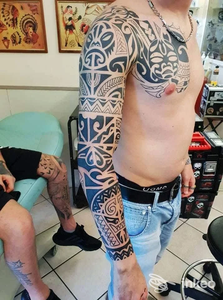 Grosso tatuaggio tribale a manica con estensione sul petto, fotografato in studio su un uomo. Bottatattoo, Roma.